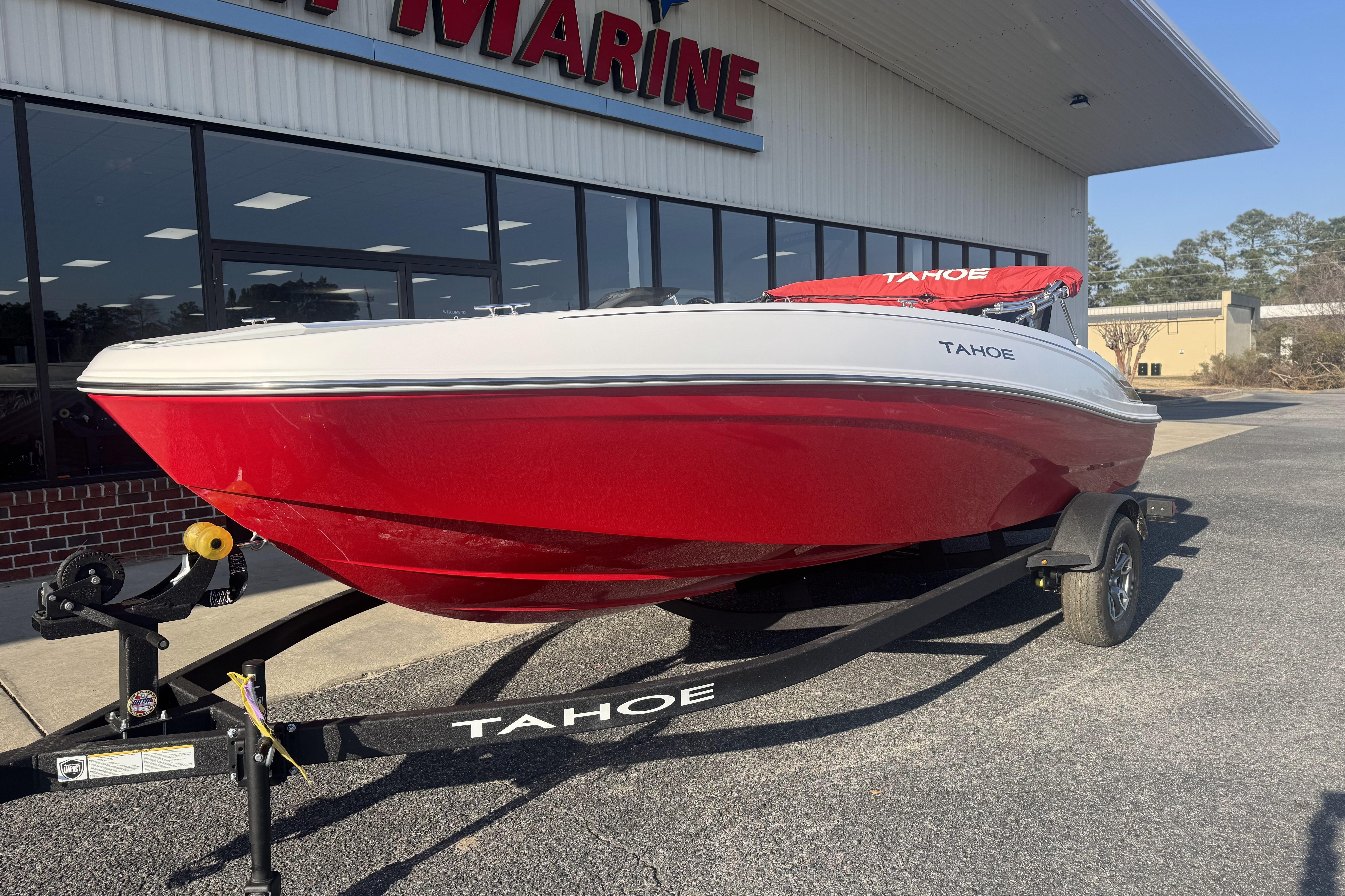 2026 Tahoe T18 boat in vibrant red on a trailer outside a marine store.