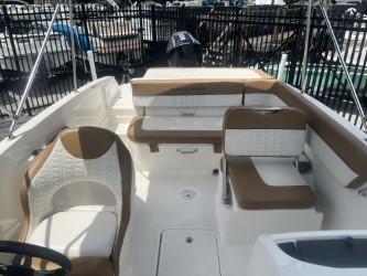 2022 Bayliner VR6 boat interior with white and brown seating, docked near a fence.
