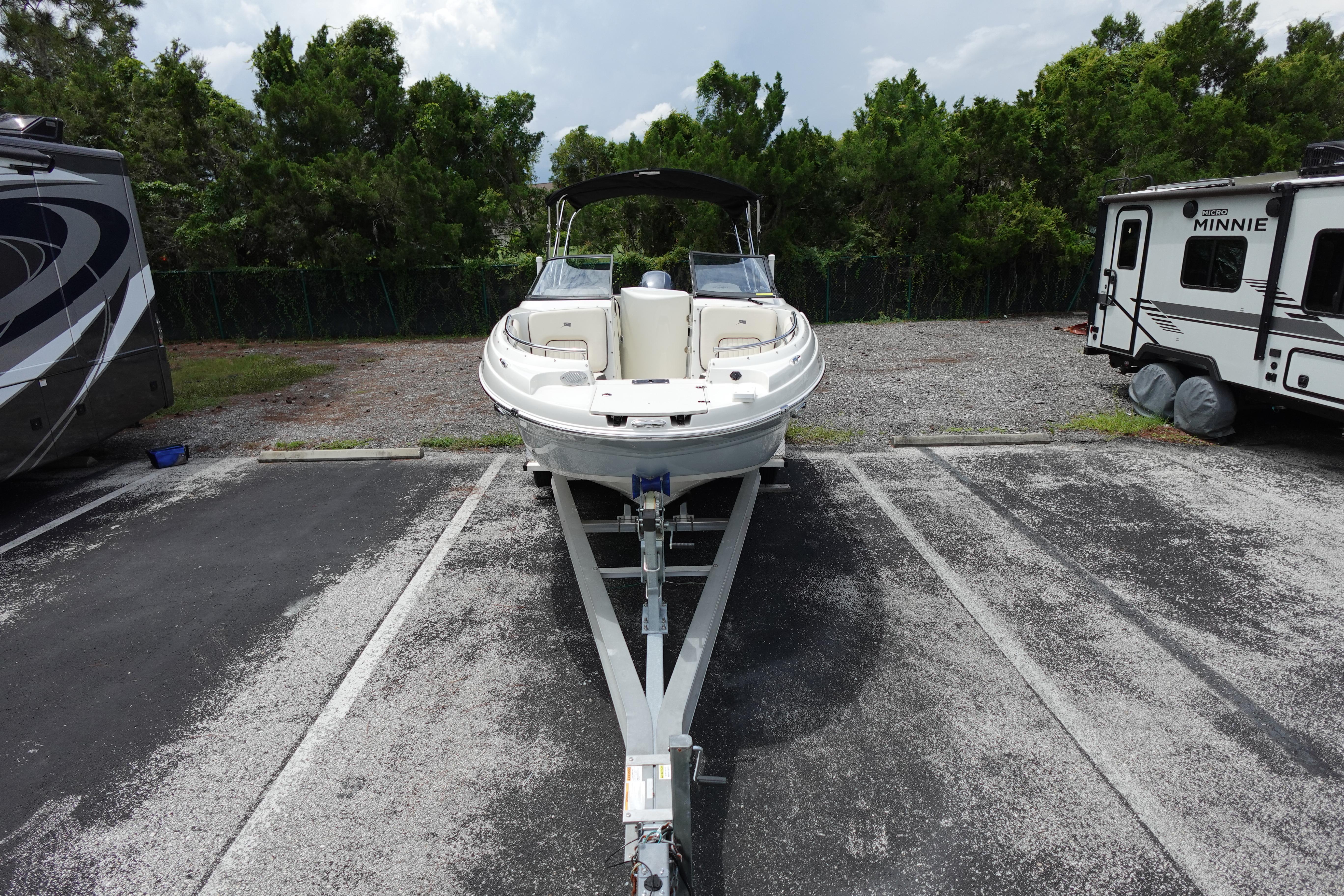 2022 Stingray 231 DC boat on trailer in parking lot, surrounded by trees and RVs.