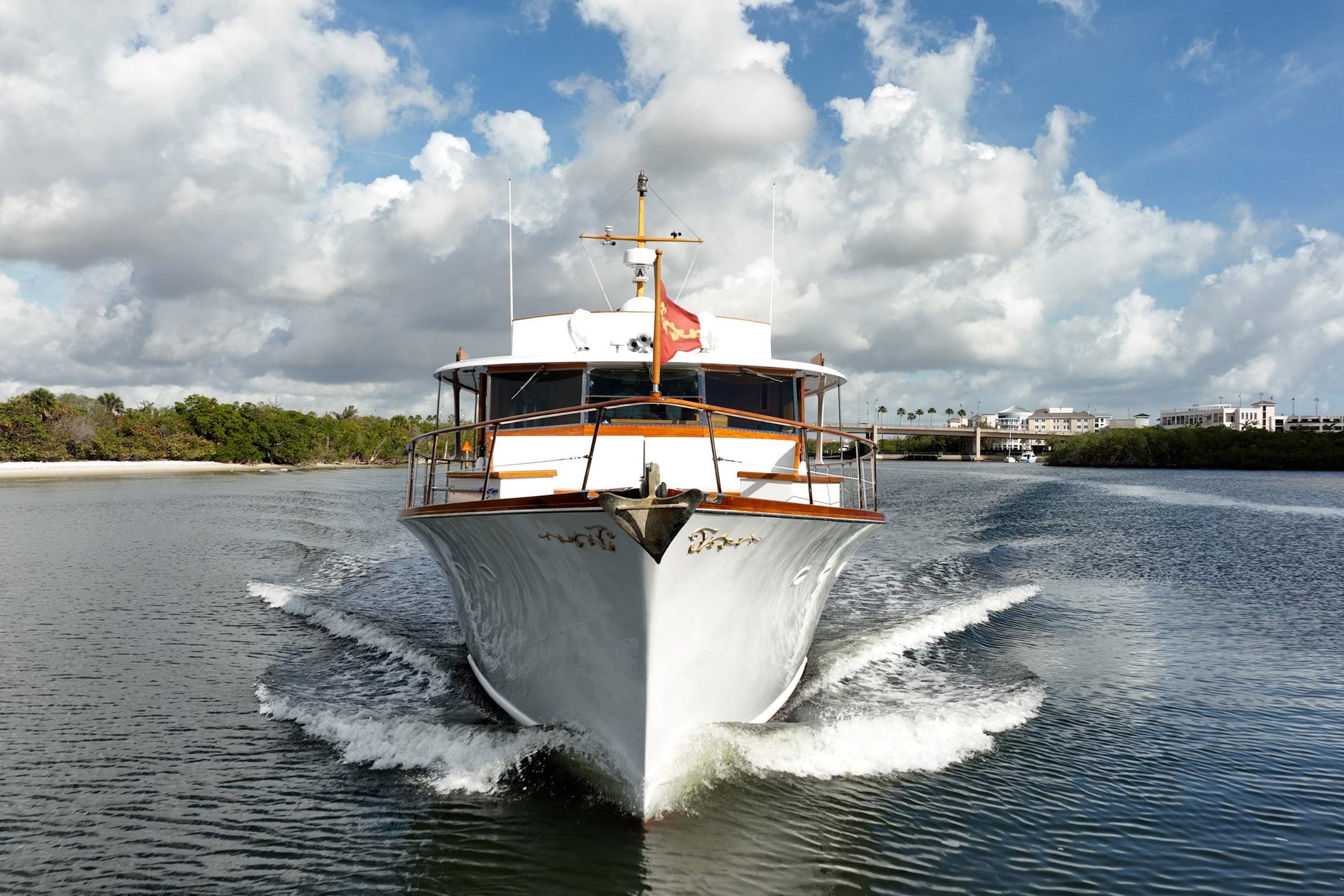 1972 Trumpy 72 Motor Yacht cruising on a scenic waterway under a partly cloudy sky.
