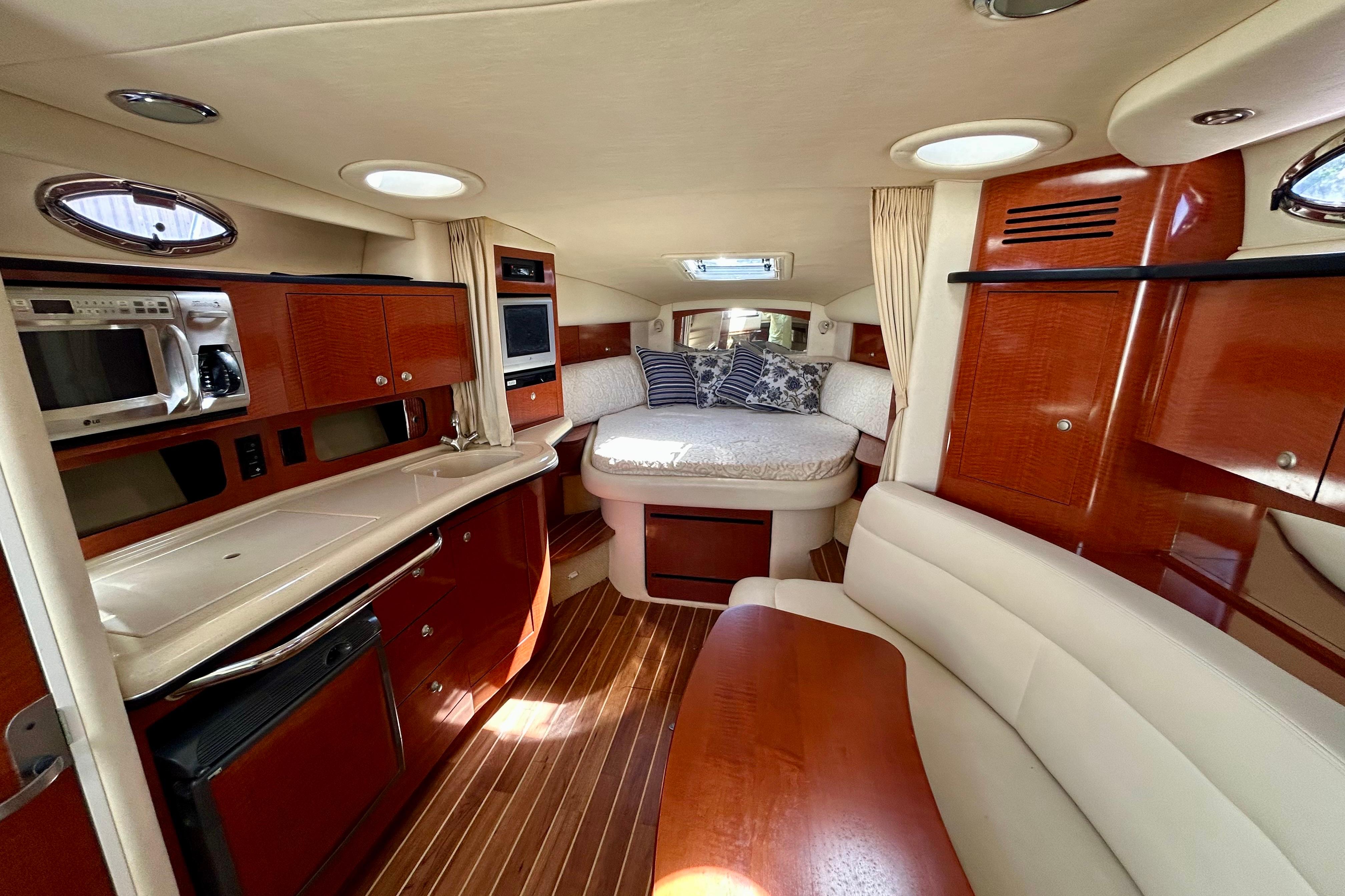 Luxurious interior of 2005 Sea Ray Sundancer 320 yacht with wood finishes and cozy seating.