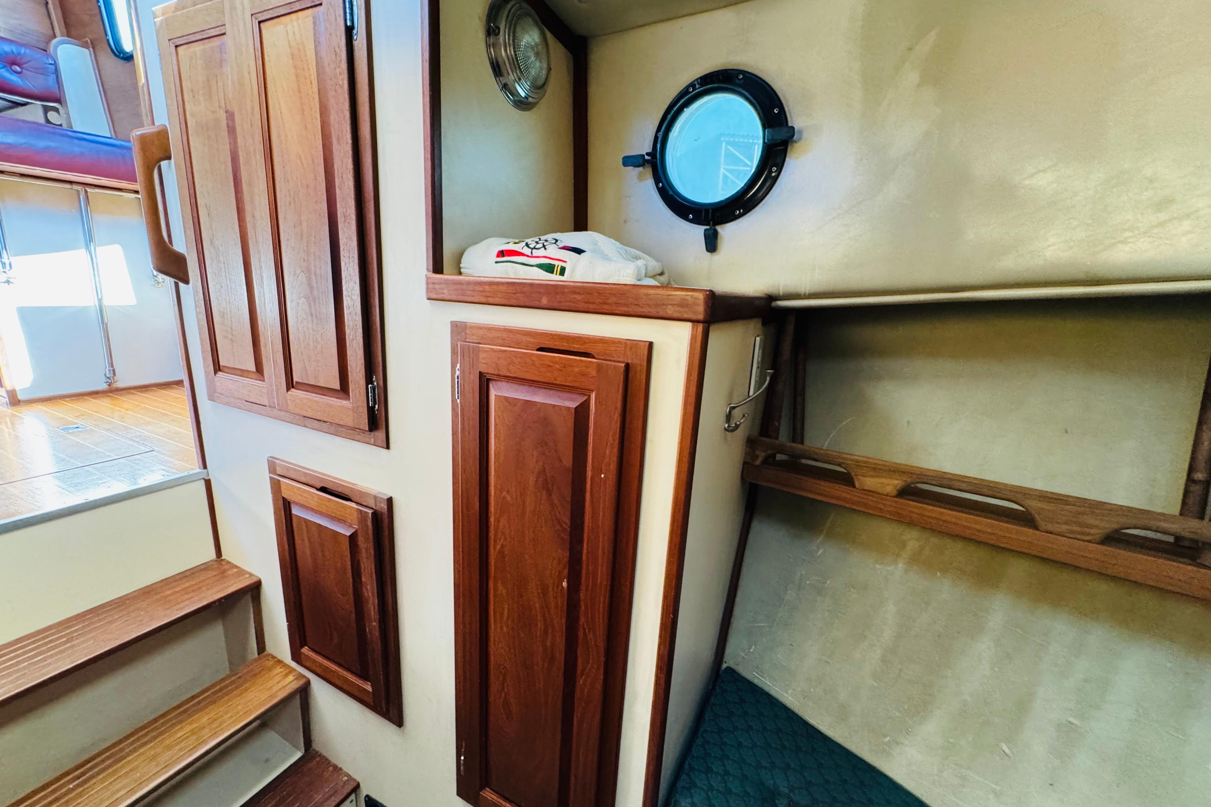 Interior of a 1996 Nordic Tug 32, featuring wooden cabinetry and a porthole window.