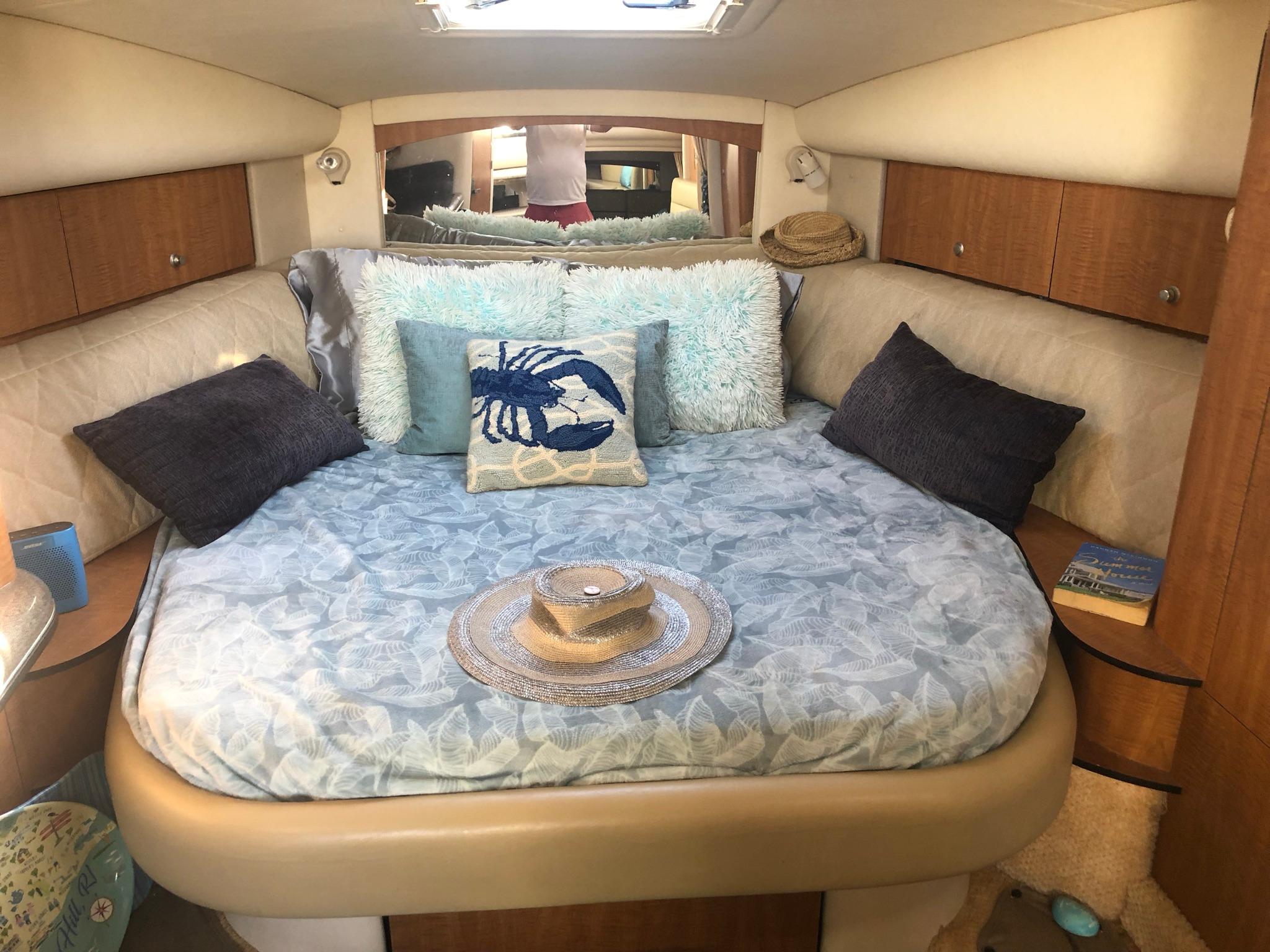 Cozy cabin interior of 2006 Sea Ray 320 Sundancer with plush bedding and decorative pillows.