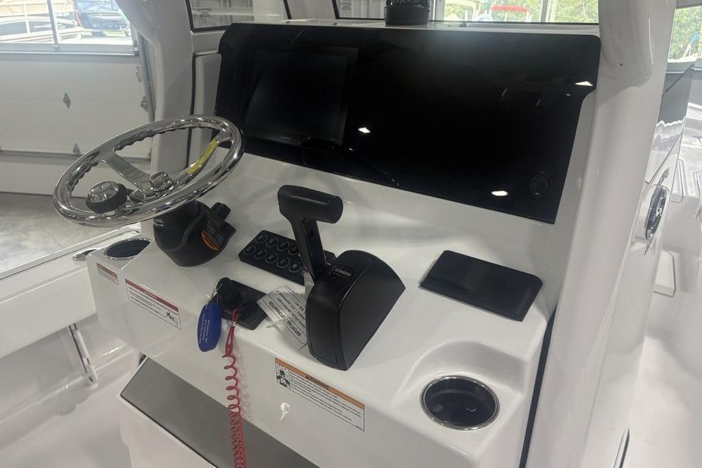 2026 Sportsman Masters 227 boat console with steering wheel and controls in a showroom.