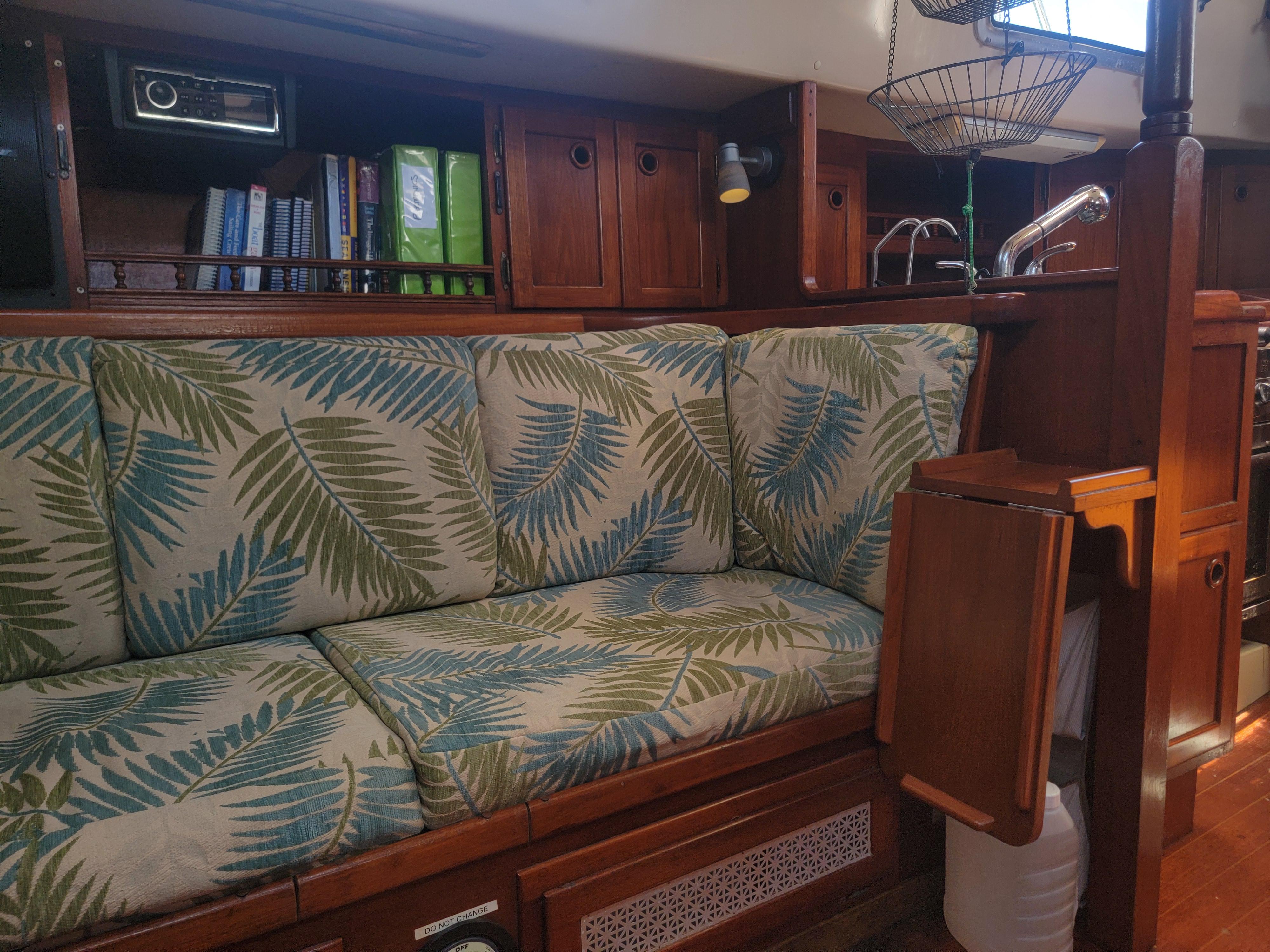 Interior of a 1987 Bayfield 36 sailboat with tropical-patterned cushions and wooden cabinetry.