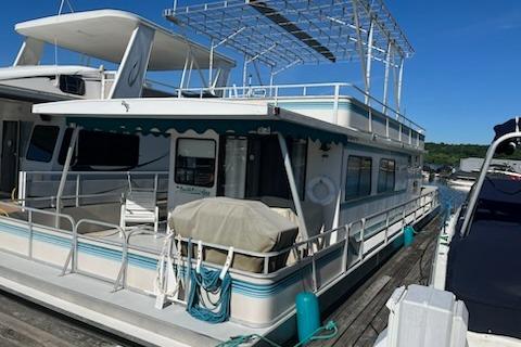 1994 PlayCraft 5215 houseboat docked, featuring upper deck and covered seating area.