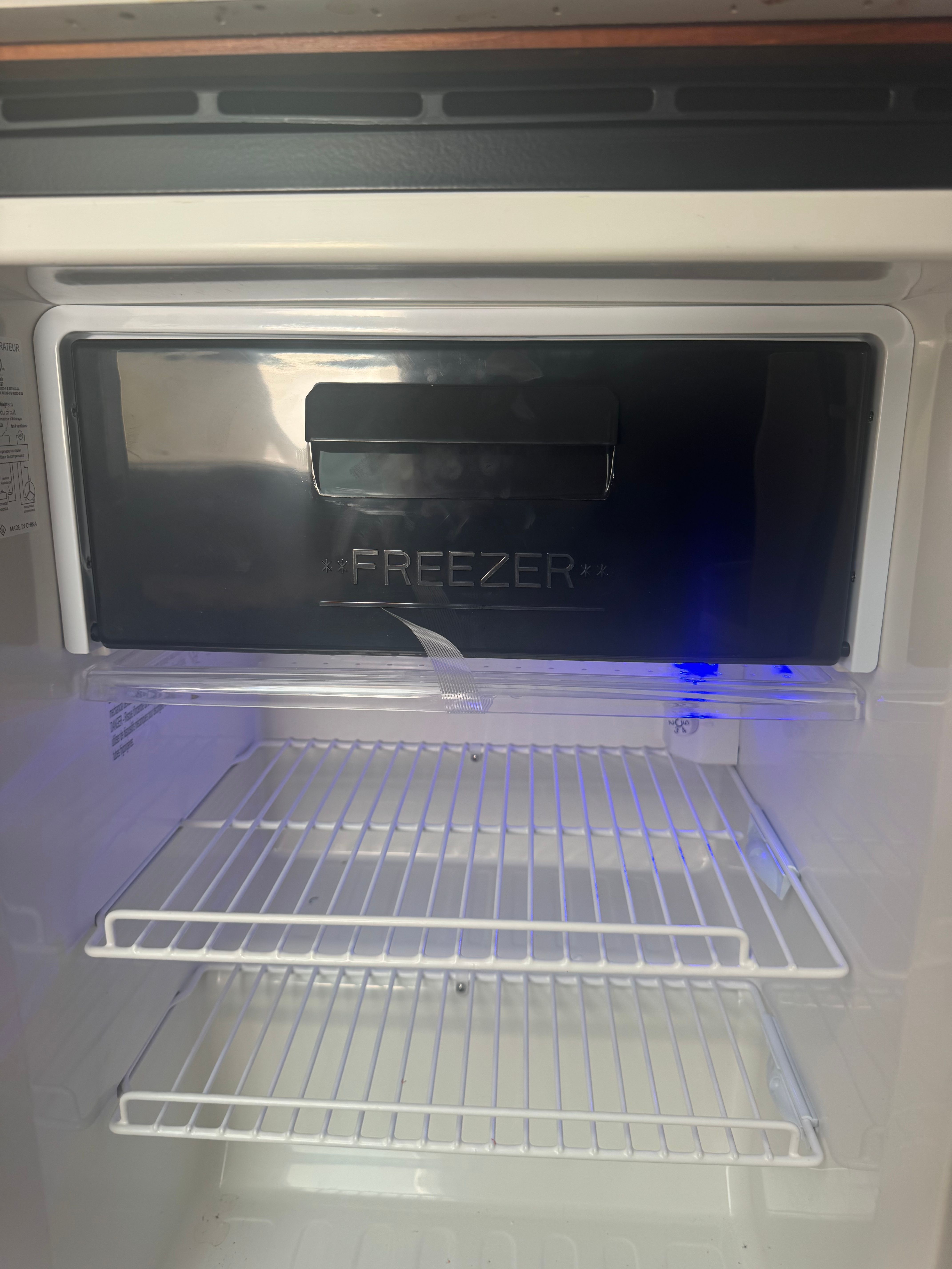 A refrigerator with two wire shelves and a top freezer compartment.