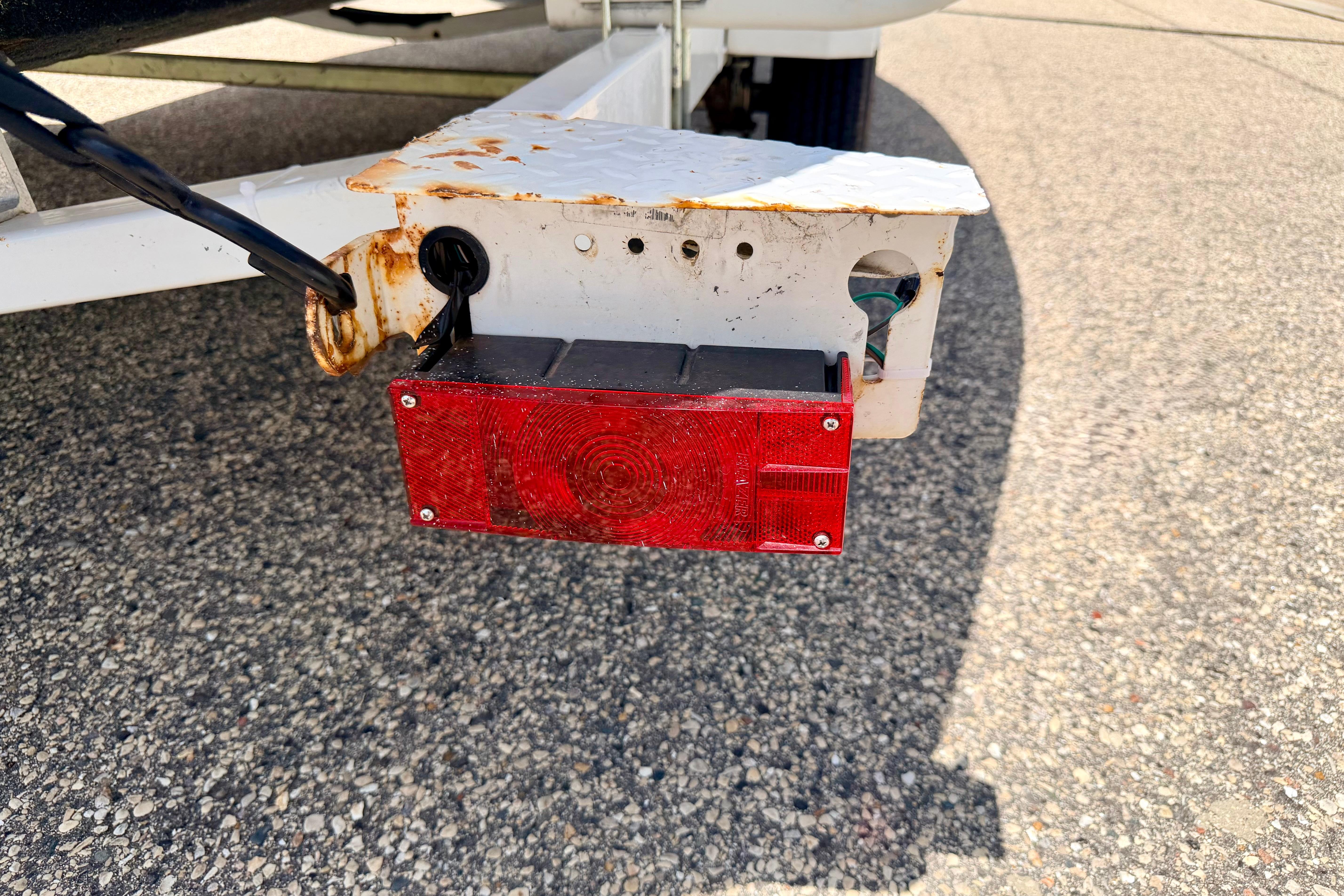Rusty trailer light on a 2004 Bombardier SEADOO Utopia 185, parked on asphalt.