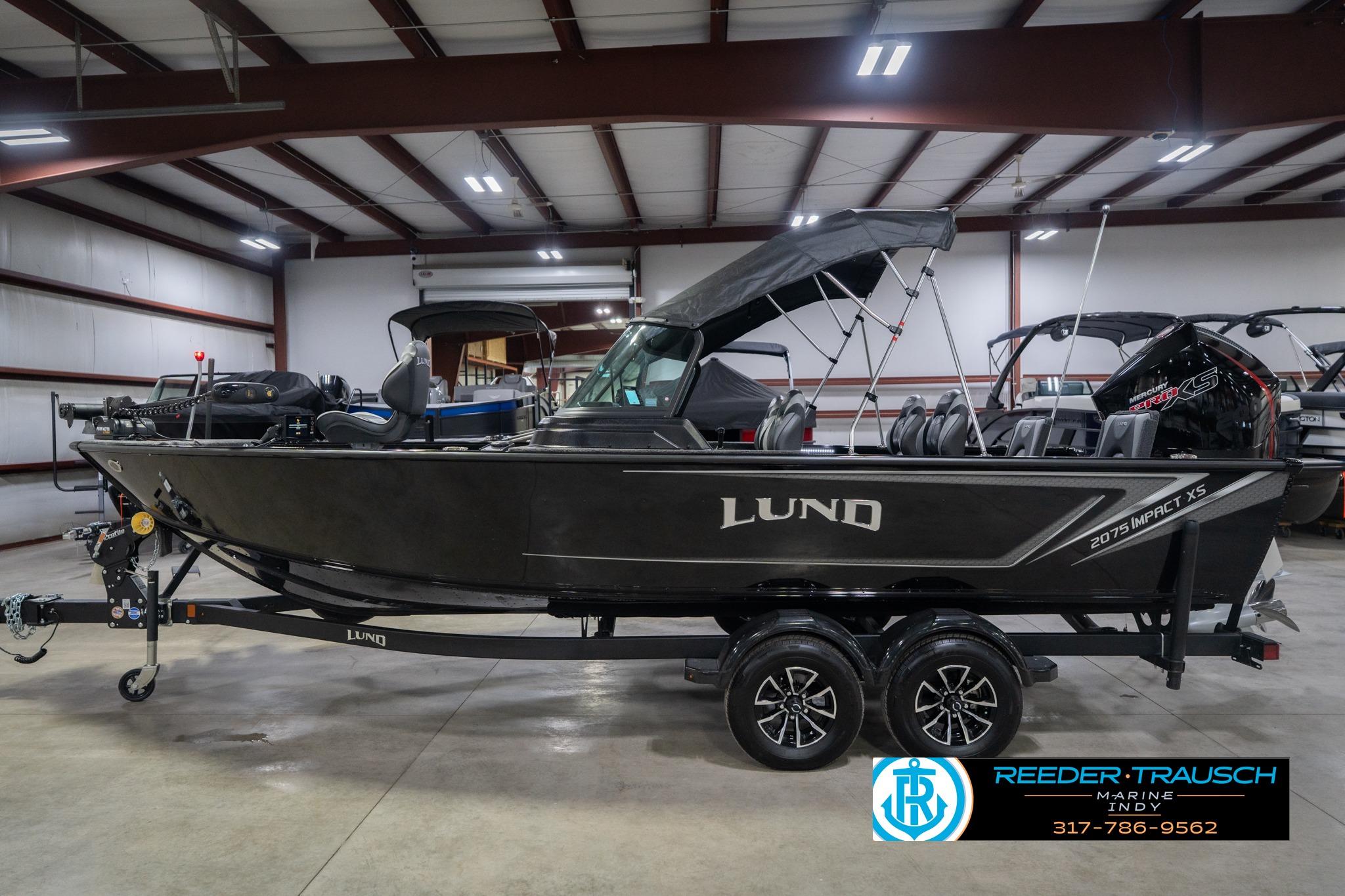 2026 Lund 2075 Impact XS boat in showroom, side view with trailer and canopy.