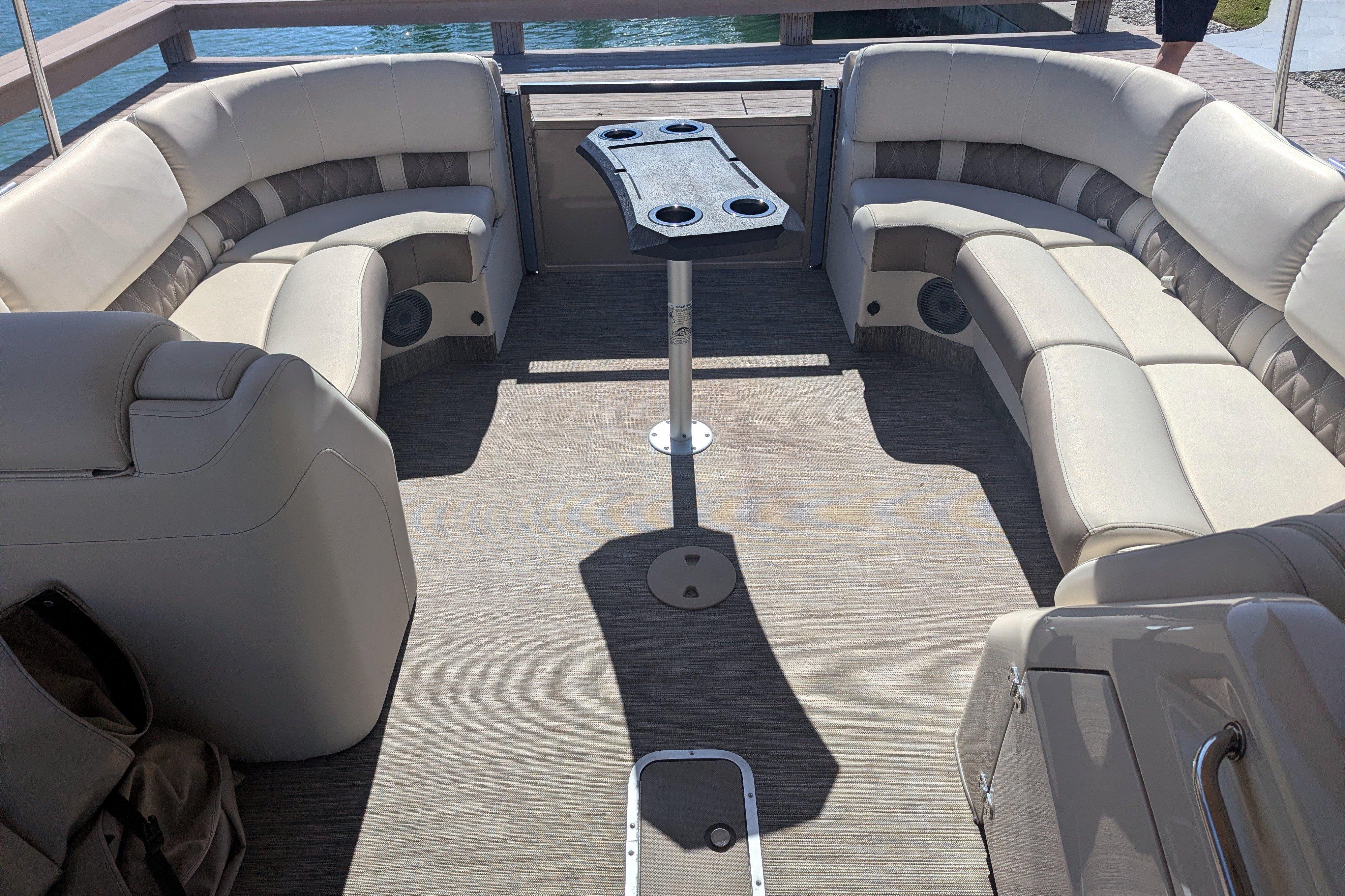 2022 Bennington QXFBAX2 boat interior with beige seating and central table.