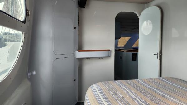 Interior of 1991 Custom Morelli-Miller boat with bed, cabinets, and open door.