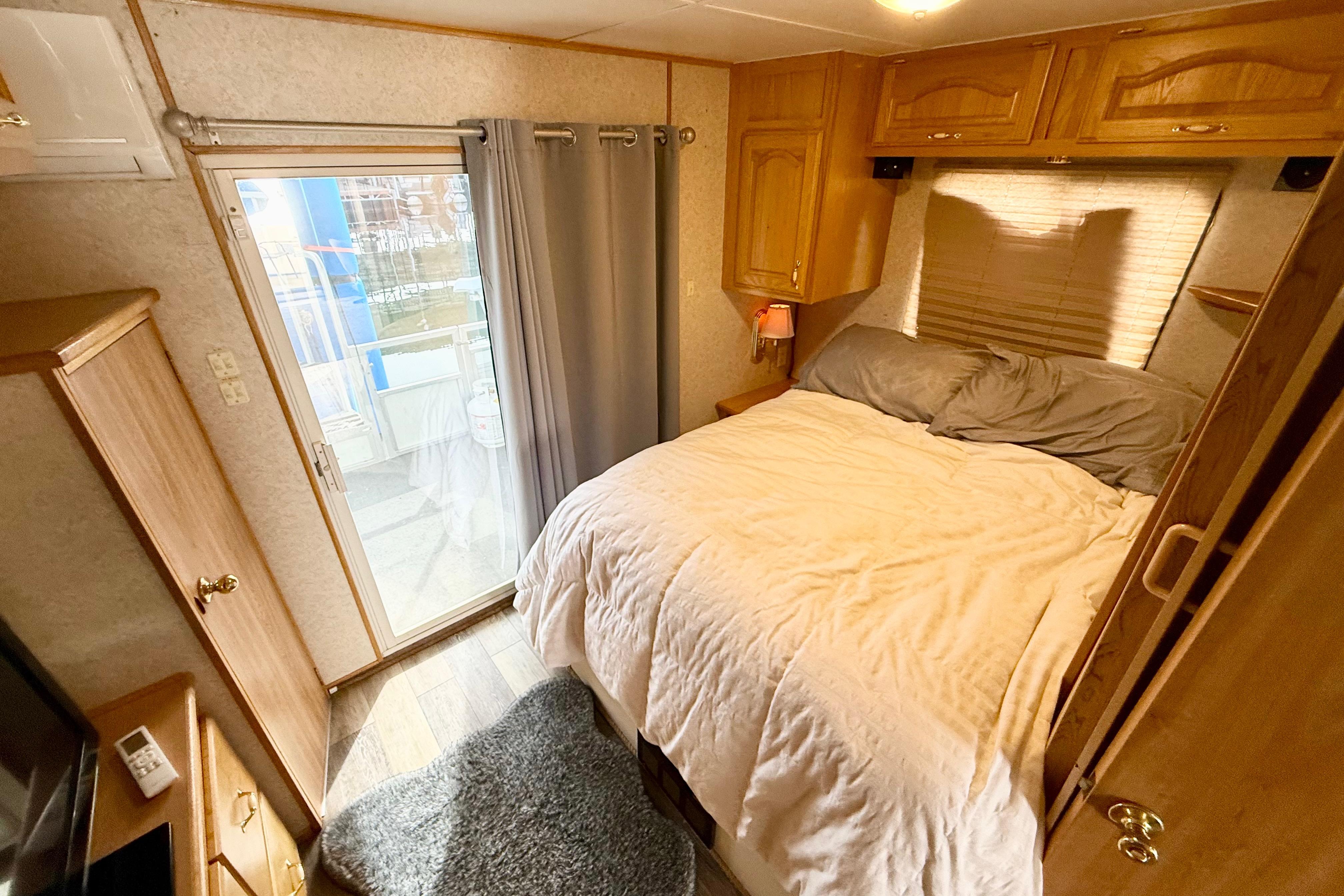 Cozy bedroom in 2006 Myacht 4313 houseboat with wooden cabinets and sliding glass door.