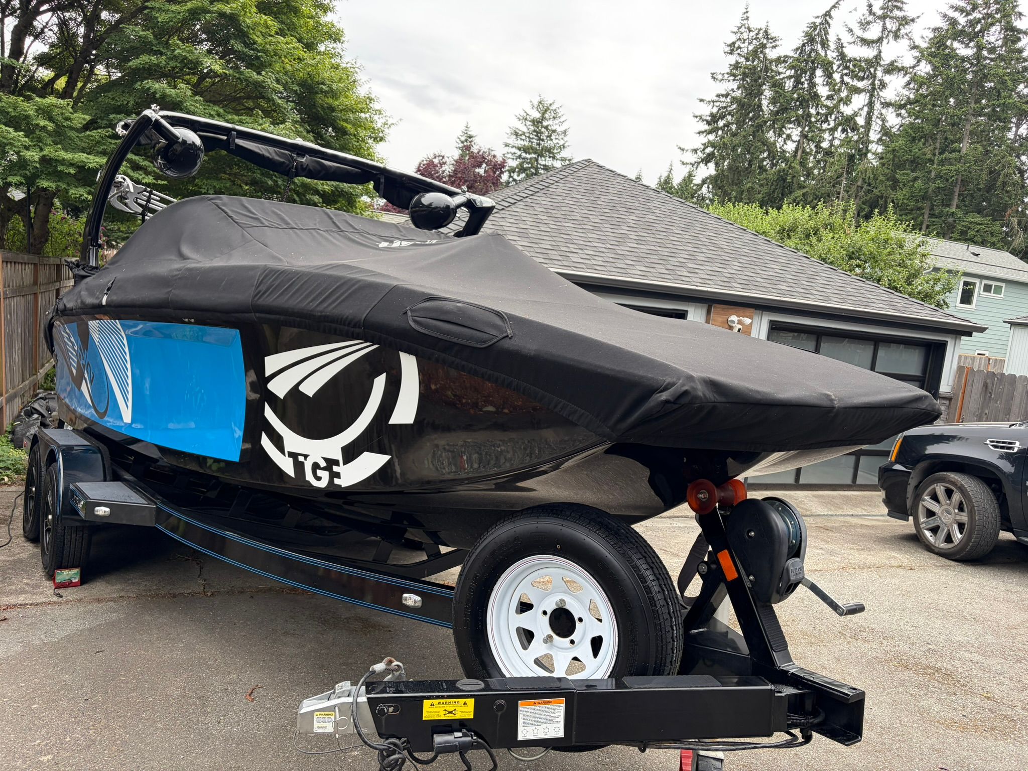 A 2016 Tigé RZ2 boat on a trailer, covered, parked in a driveway.