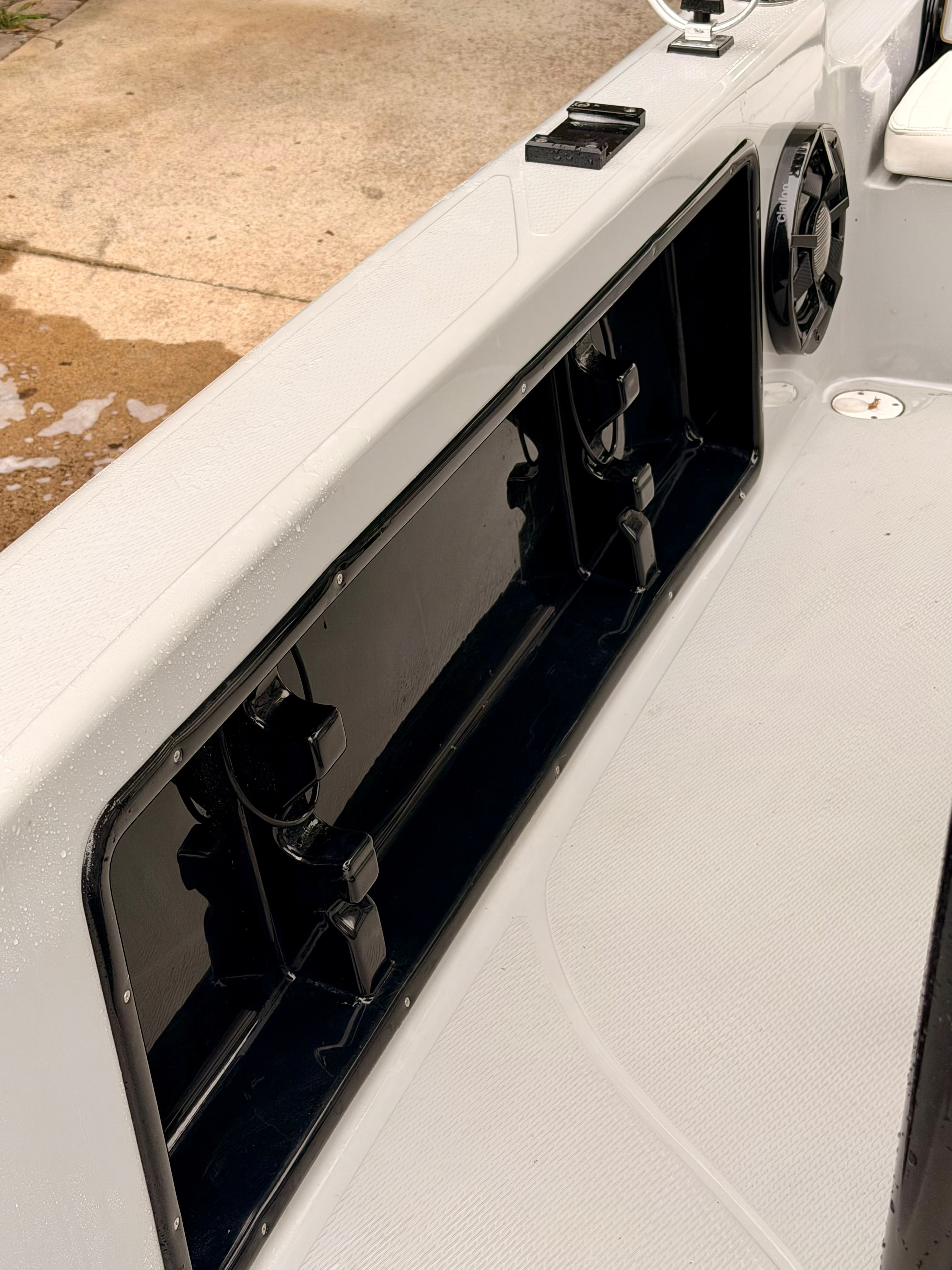 Close-up of a boat deck with black storage compartments and a speaker.