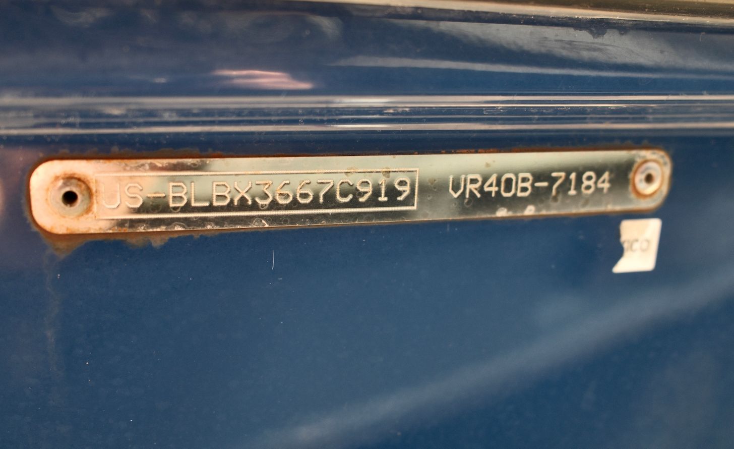 Close-up of a metal plaque with serial number on a blue boat hull.