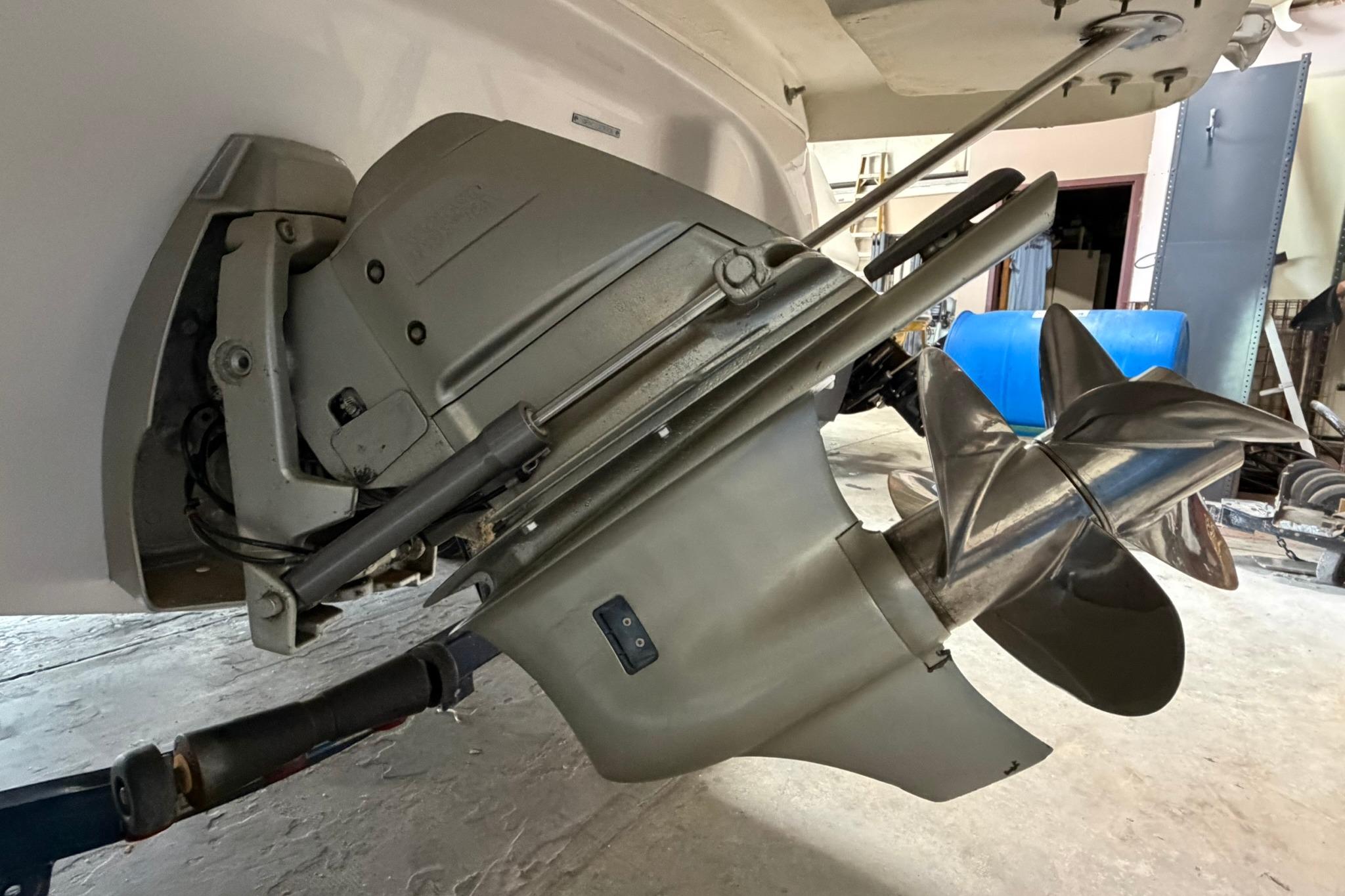 Close-up of a 2008 Four Winns V248 boat propeller and outdrive in a workshop.