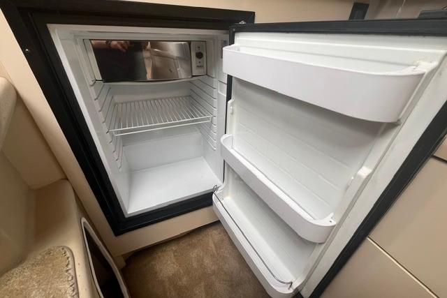 Open refrigerator inside 2004 Cruisers Yachts 3372 Express, showcasing interior storage space.