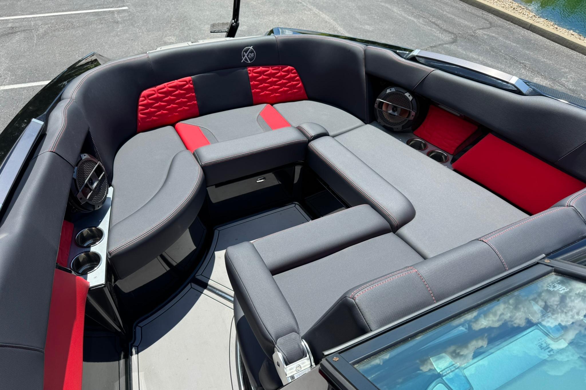 2021 MasterCraft X26 boat interior with red and gray seating, cup holders, and speakers.