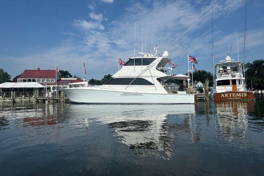 2002 Viking 61 Enclosed Bridge yacht docked at marina, flags displayed, clear sky.