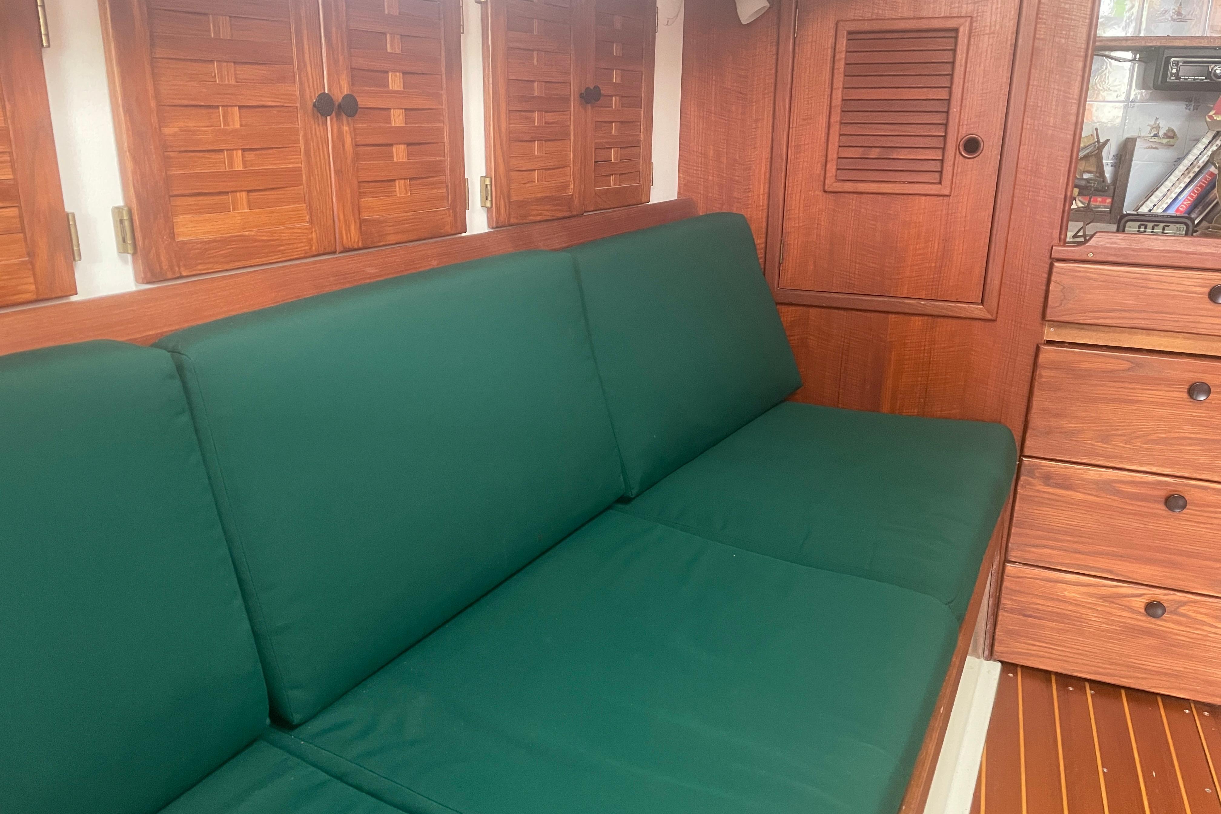 Interior of 1981 Nonsuch 30 Classic sailboat with green cushions and wooden cabinetry.