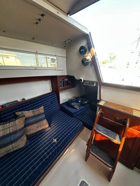 Interior of a 1985 Catalina 27 with blue seating cushions and wooden furnishings.