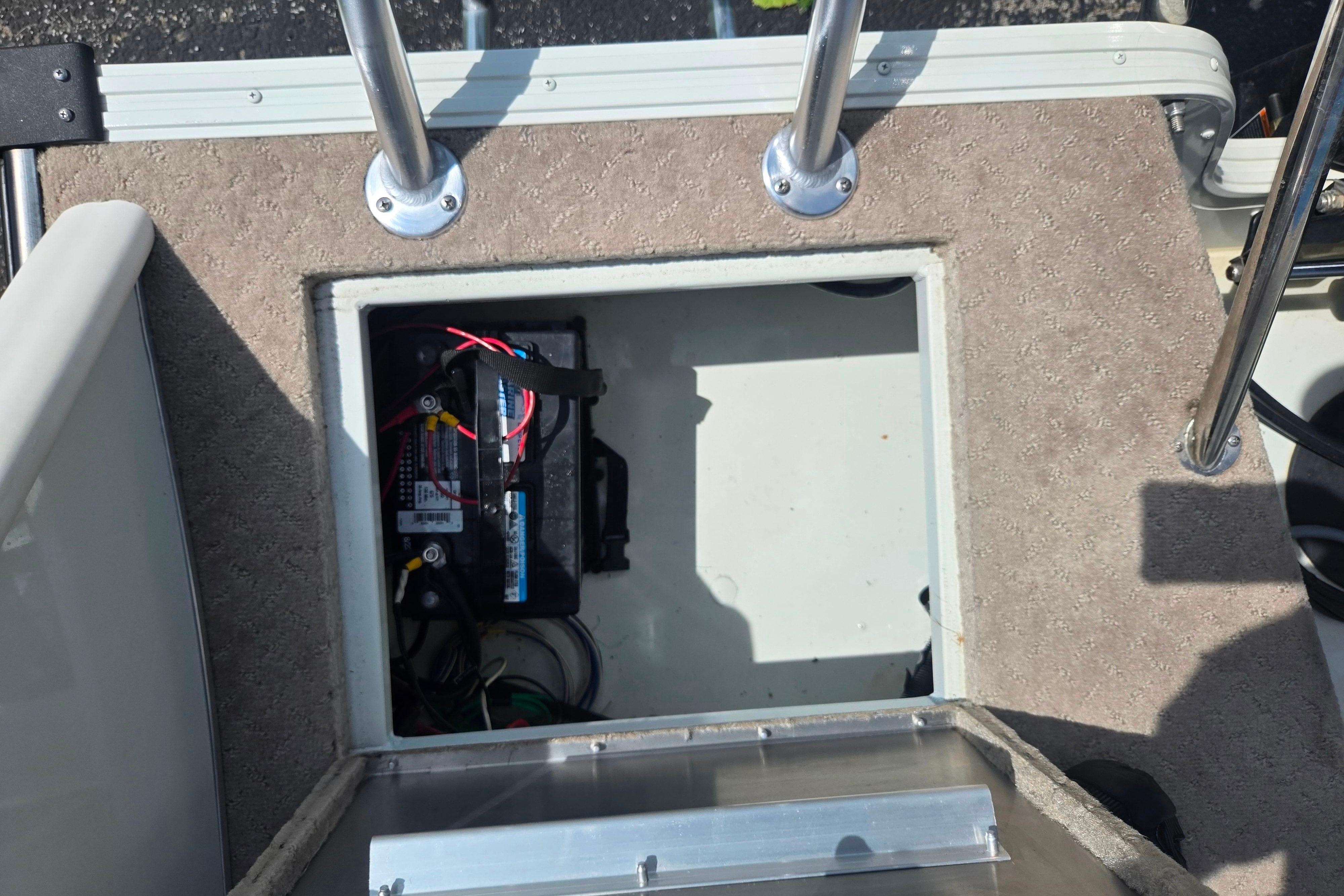 Battery compartment of a 2015 Lowe Sport Deck 224 boat, showing wiring and carpeted deck.