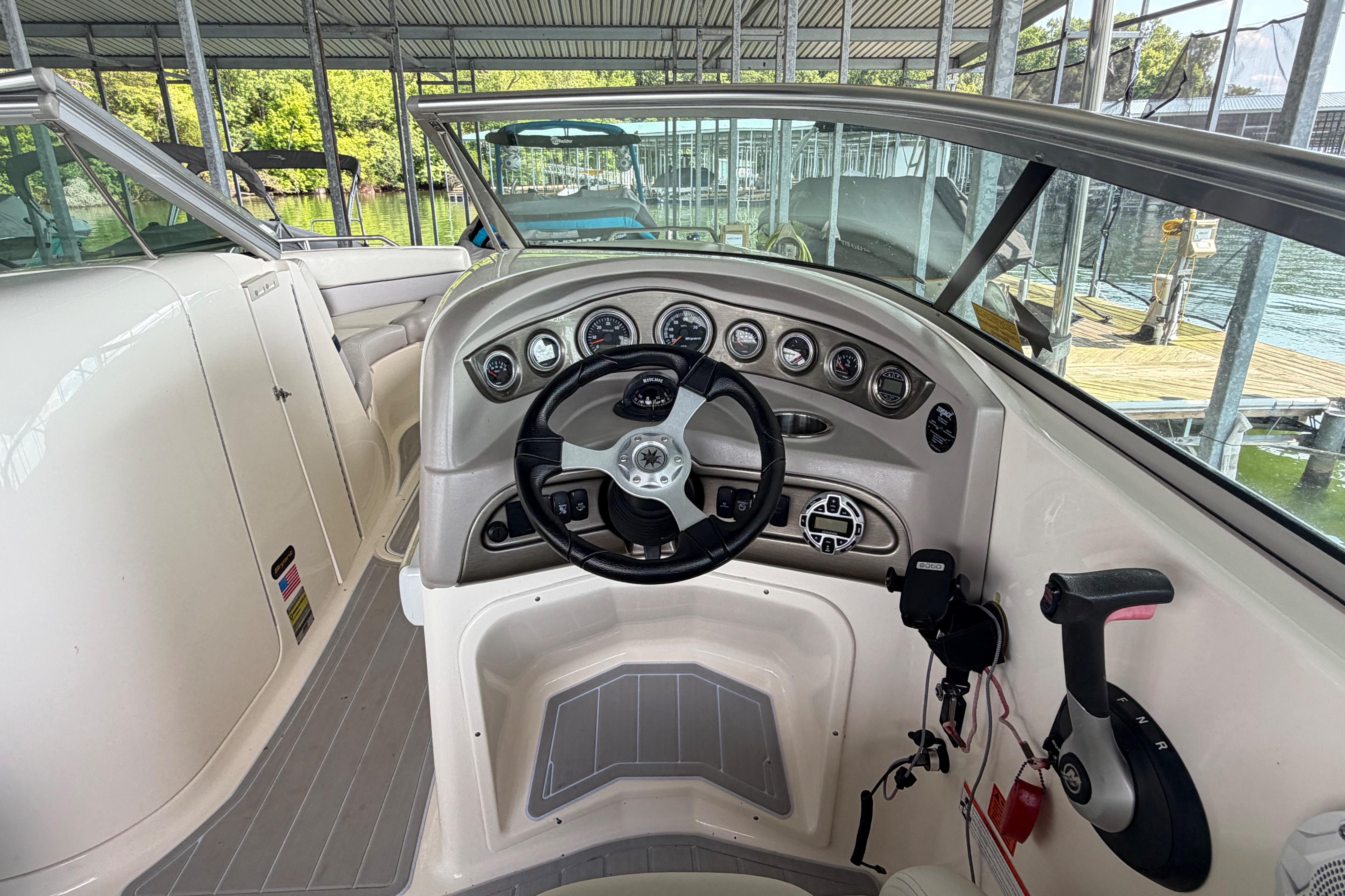 2010 Bryant 255 boat dashboard with steering wheel and control panel in a marina setting.