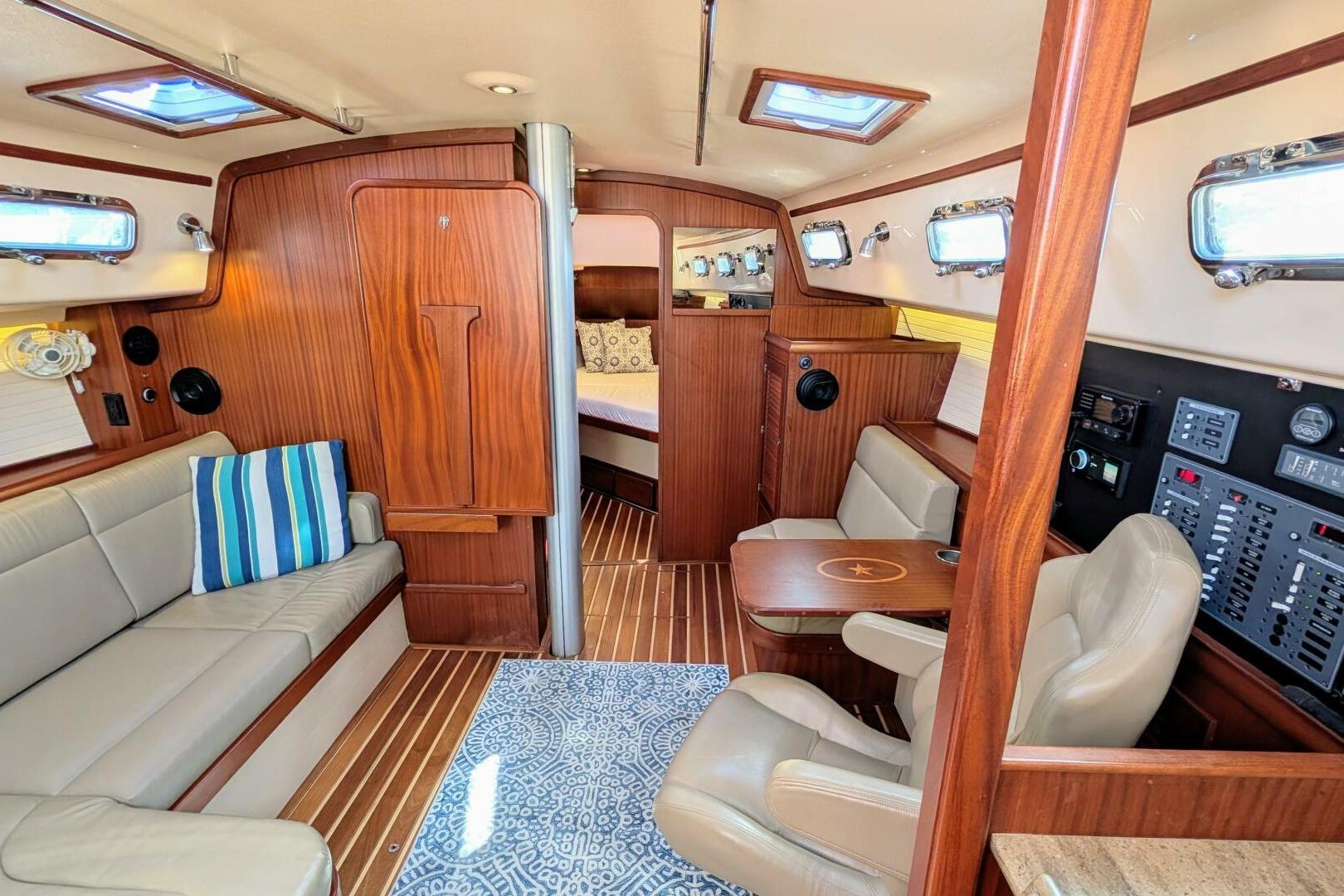 Interior of 1999 Island Packet 349 sailboat with wood paneling and cozy seating area.