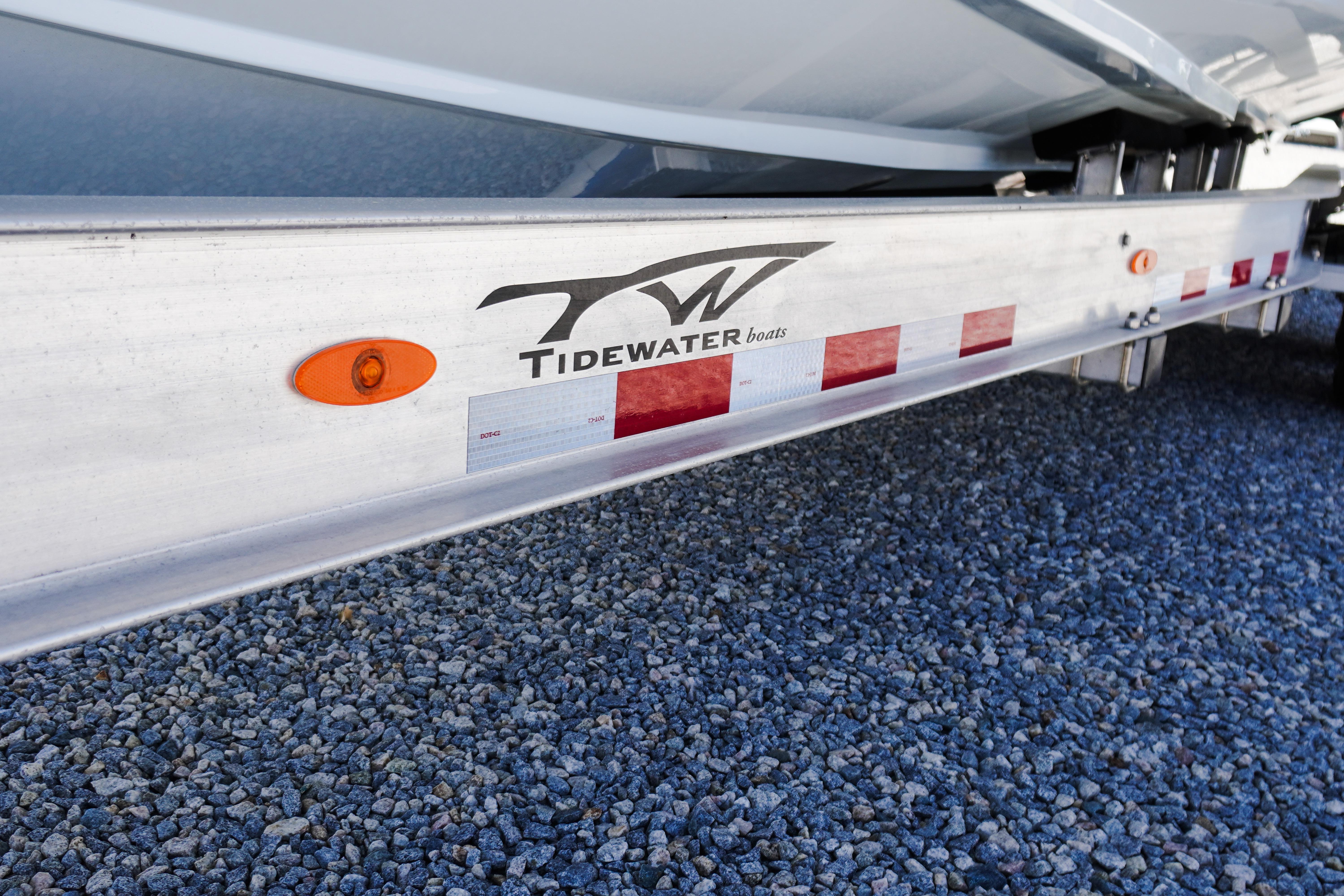 Trailer for 2026 Tidewater 302 CC Adventure boat on gravel surface.