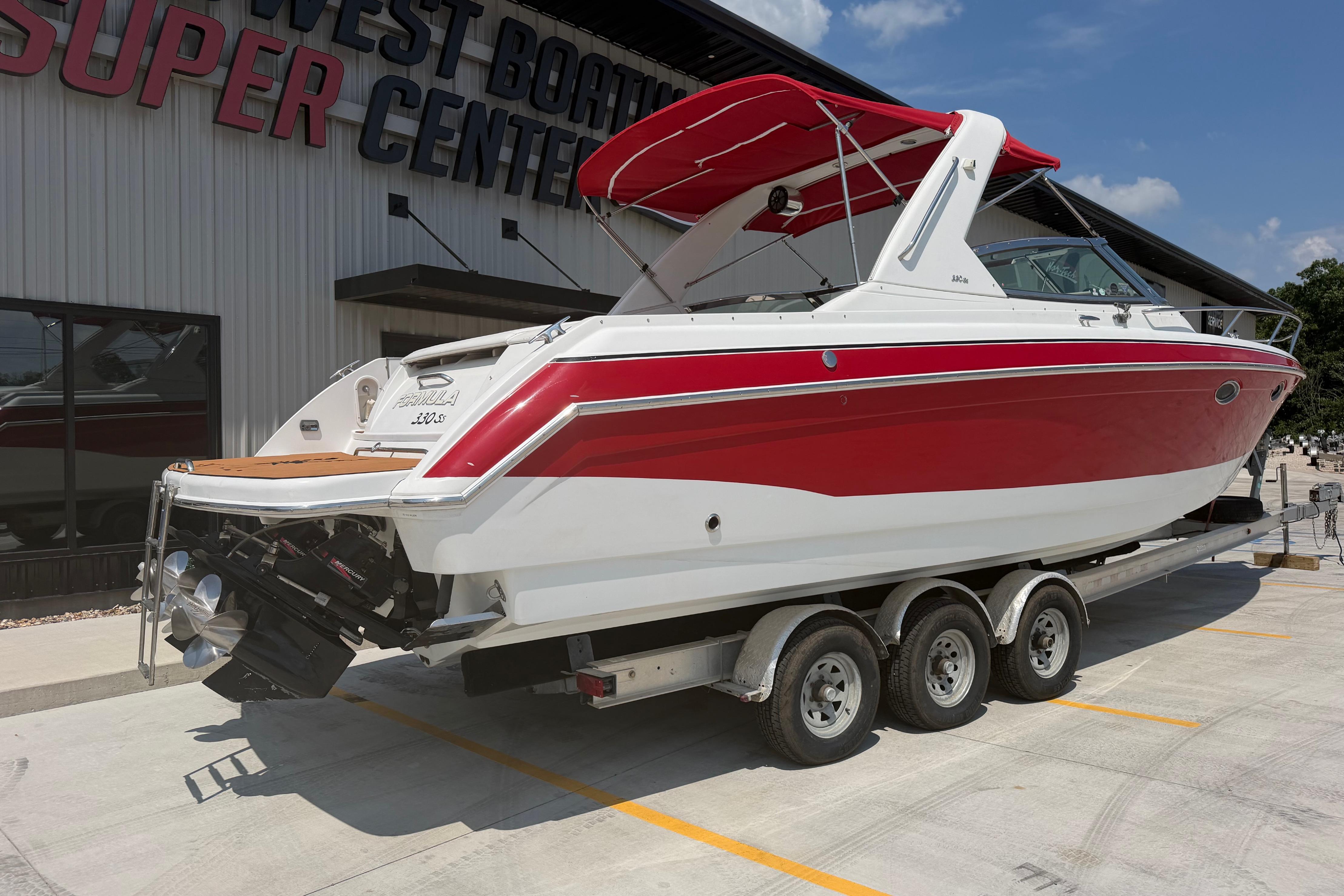 2006 Formula 330 Sun Sport boat on trailer at dealership, red and white design.