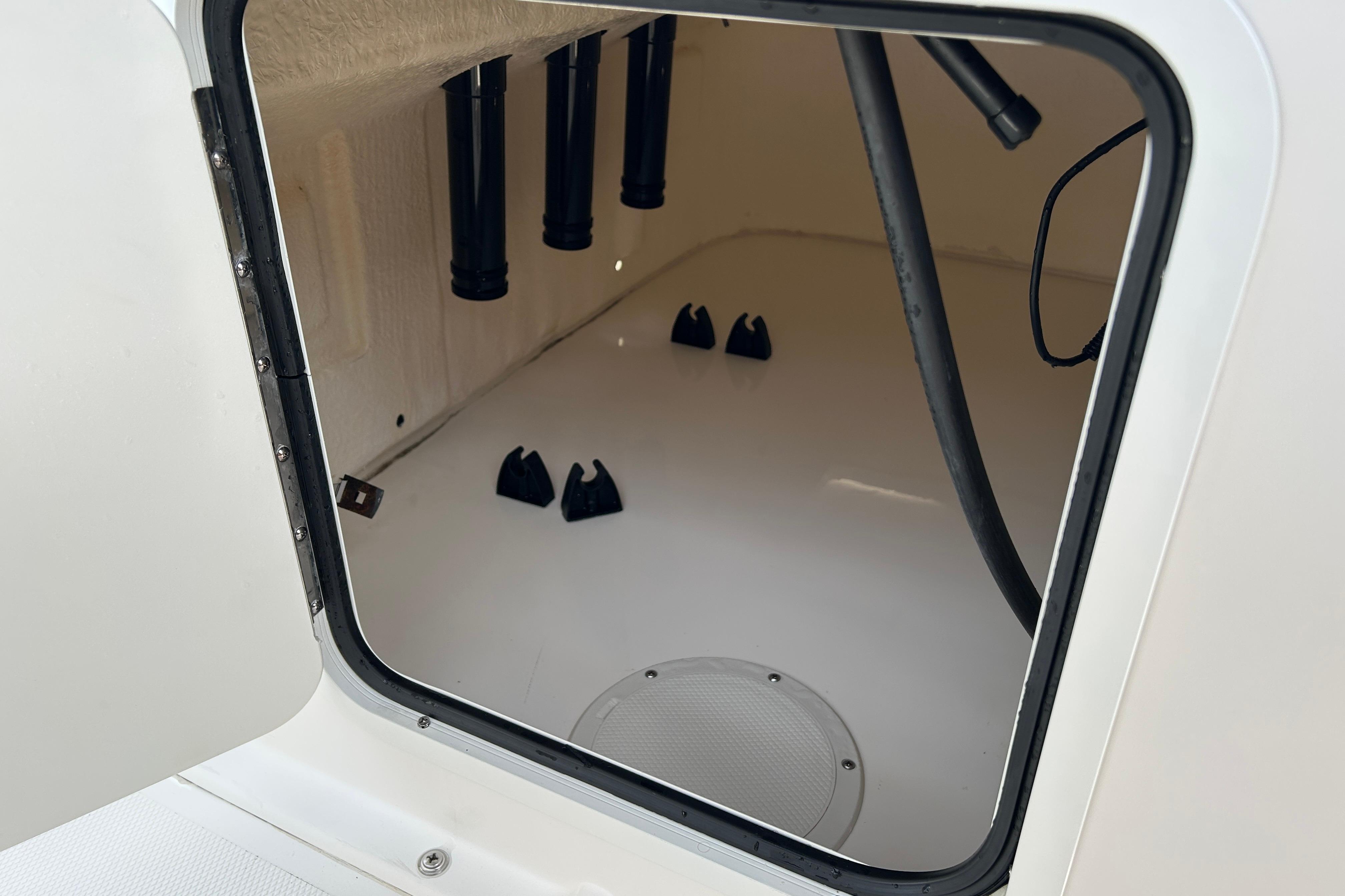 Storage compartment inside a 2018 Bayliner Element F16 boat, showing rod holders and wiring.