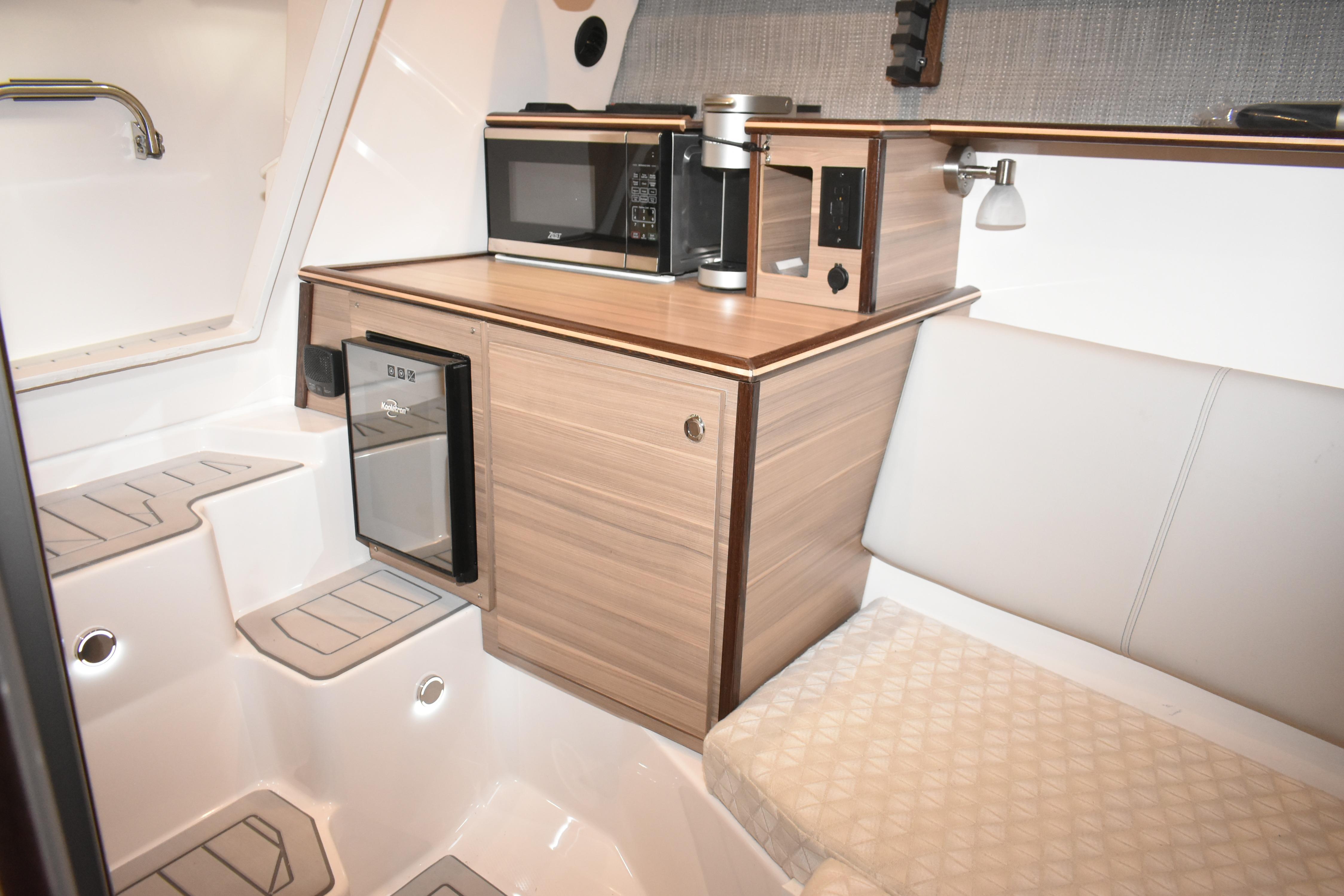 Compact kitchen area in 2025 Solara S-310 CW boat with microwave and mini fridge.