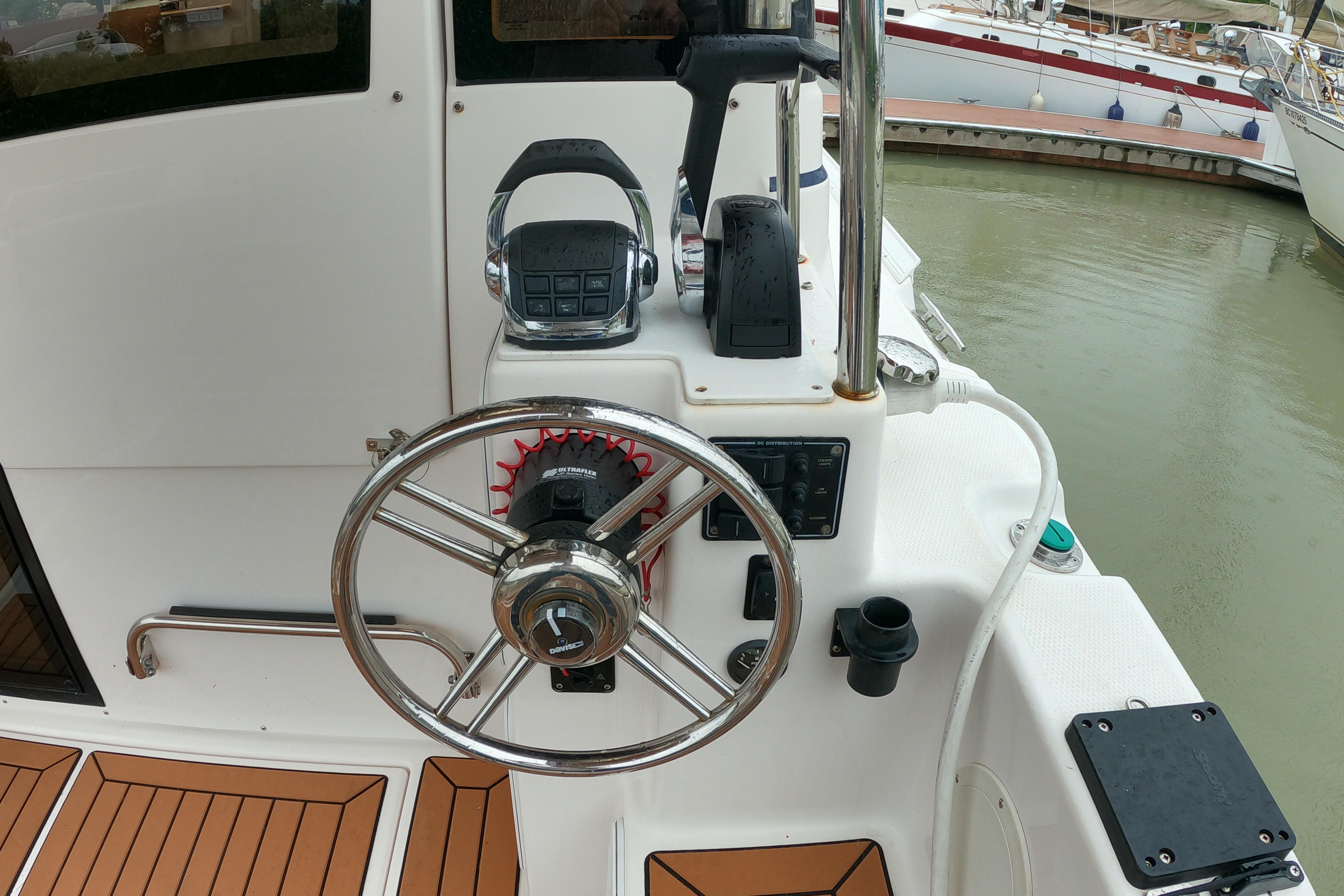 Steering wheel and controls of a 2019 Cutwater C-30 Sedan boat docked at a marina.
