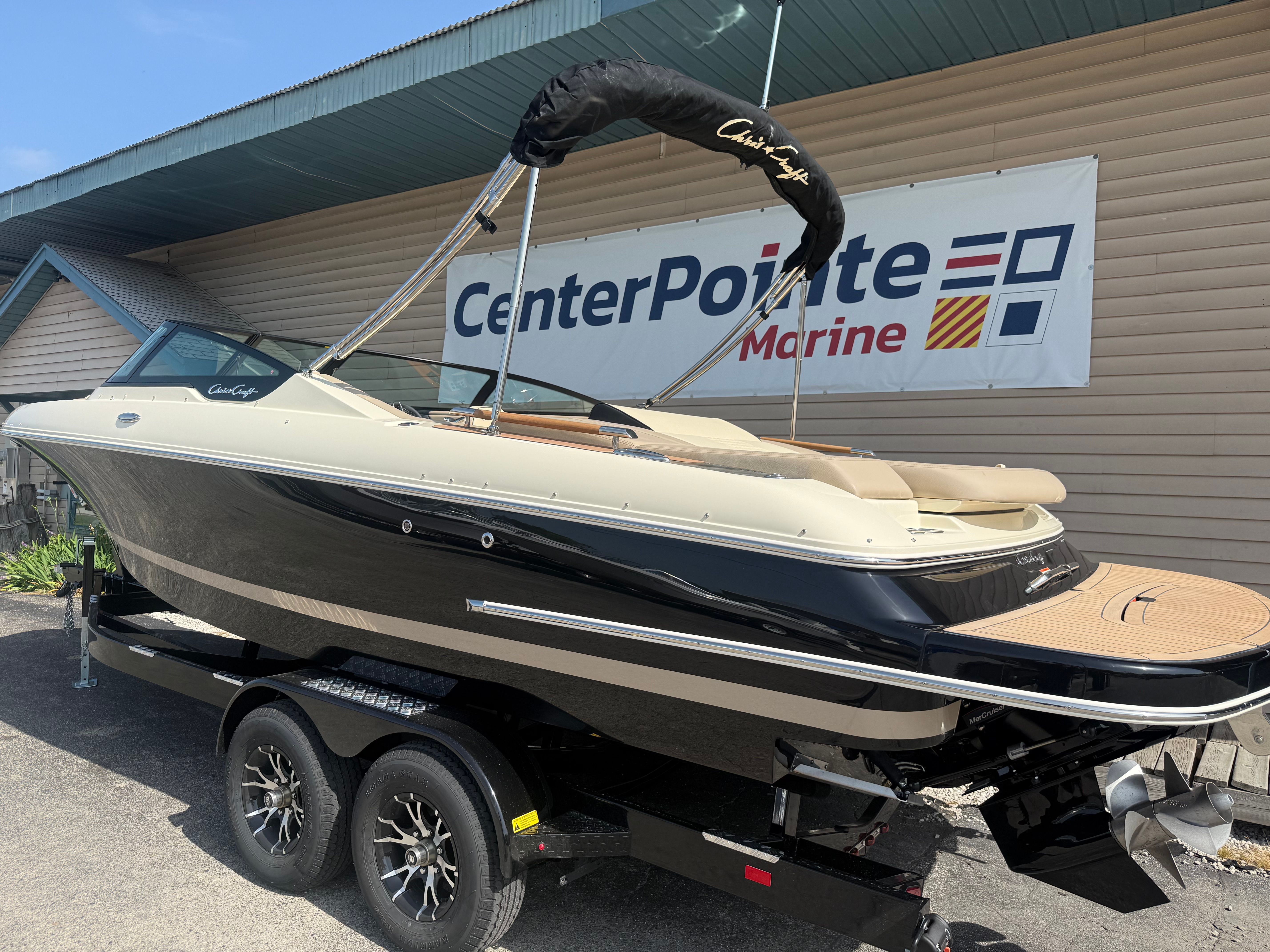 A 2027 Chris-Craft Sportster 25 on a trailer in front of a building with a marine sign.