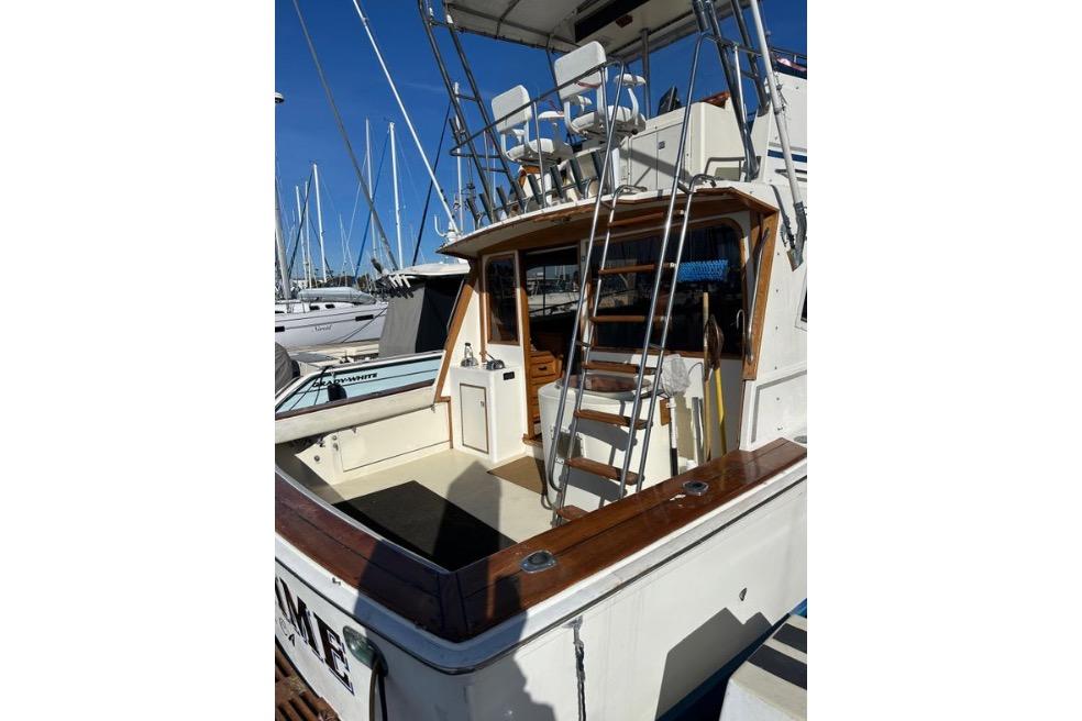 1985 Egg Harbor 33 Sedan boat with ladder and seating, docked at marina.
