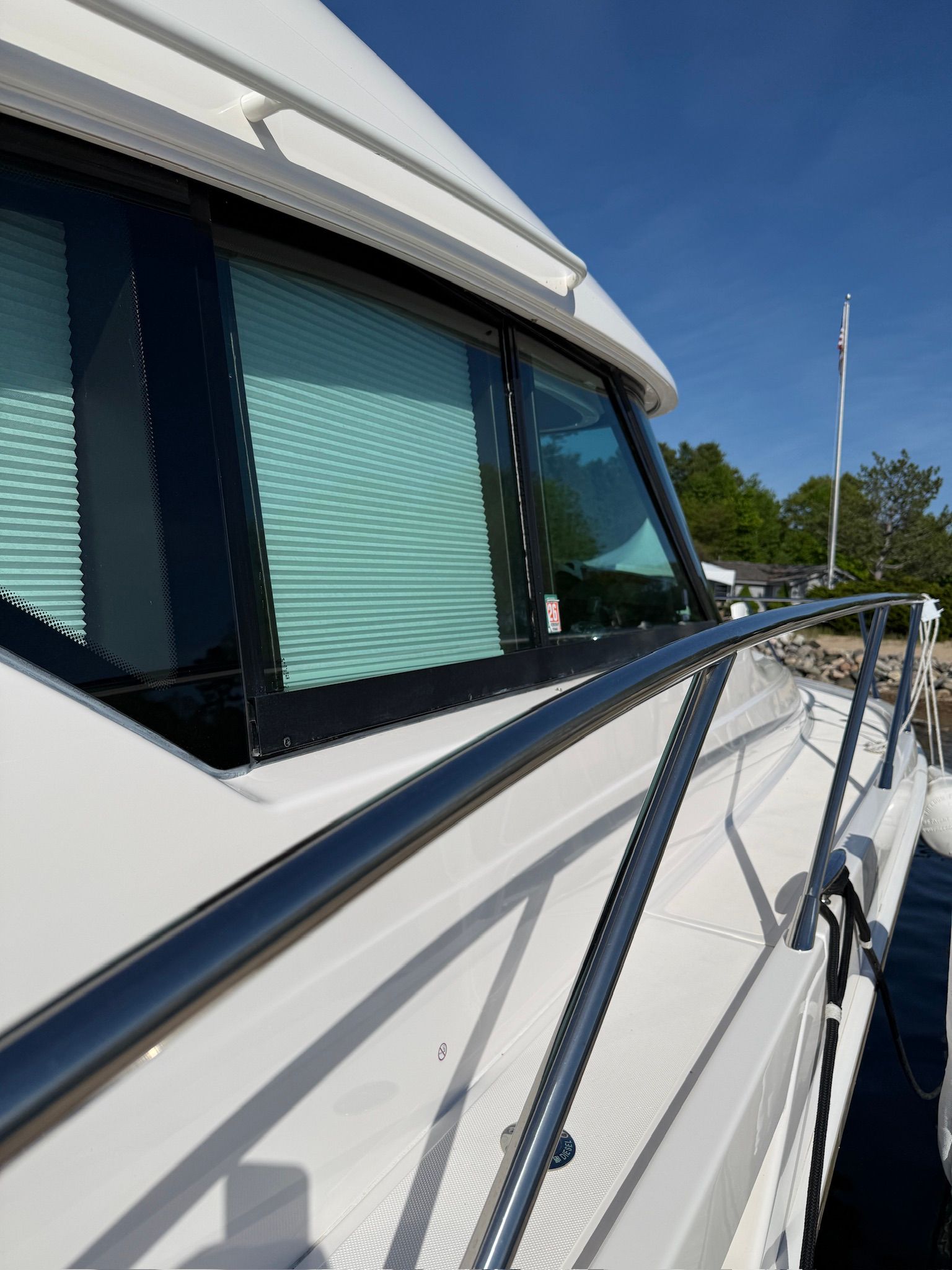 Close-up of a white boat with metal railing and windows with blinds.