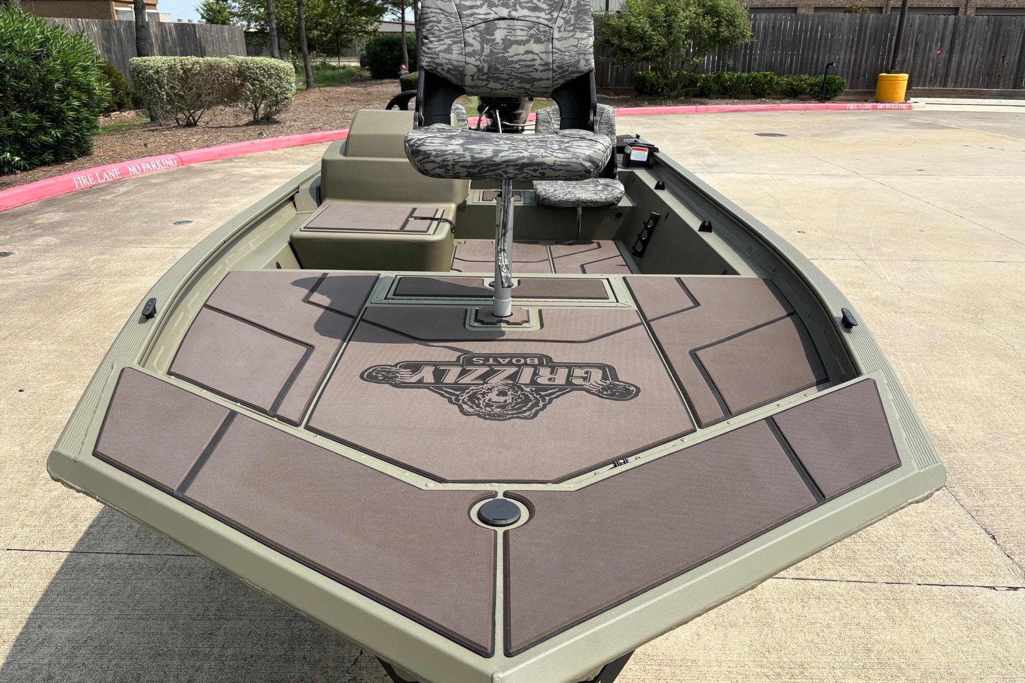2026 Tracker Grizzly 1754 SC boat with camo seating, parked on concrete.