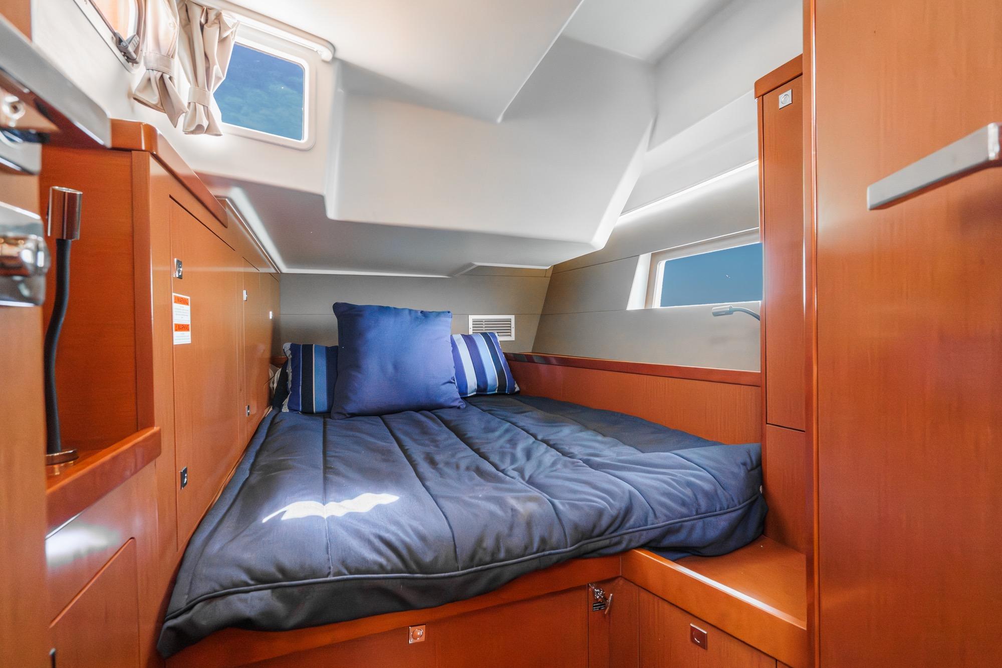 Luxurious cabin interior of 2016 Beneteau Oceanis 55 yacht with cozy bedding and wooden finishes.