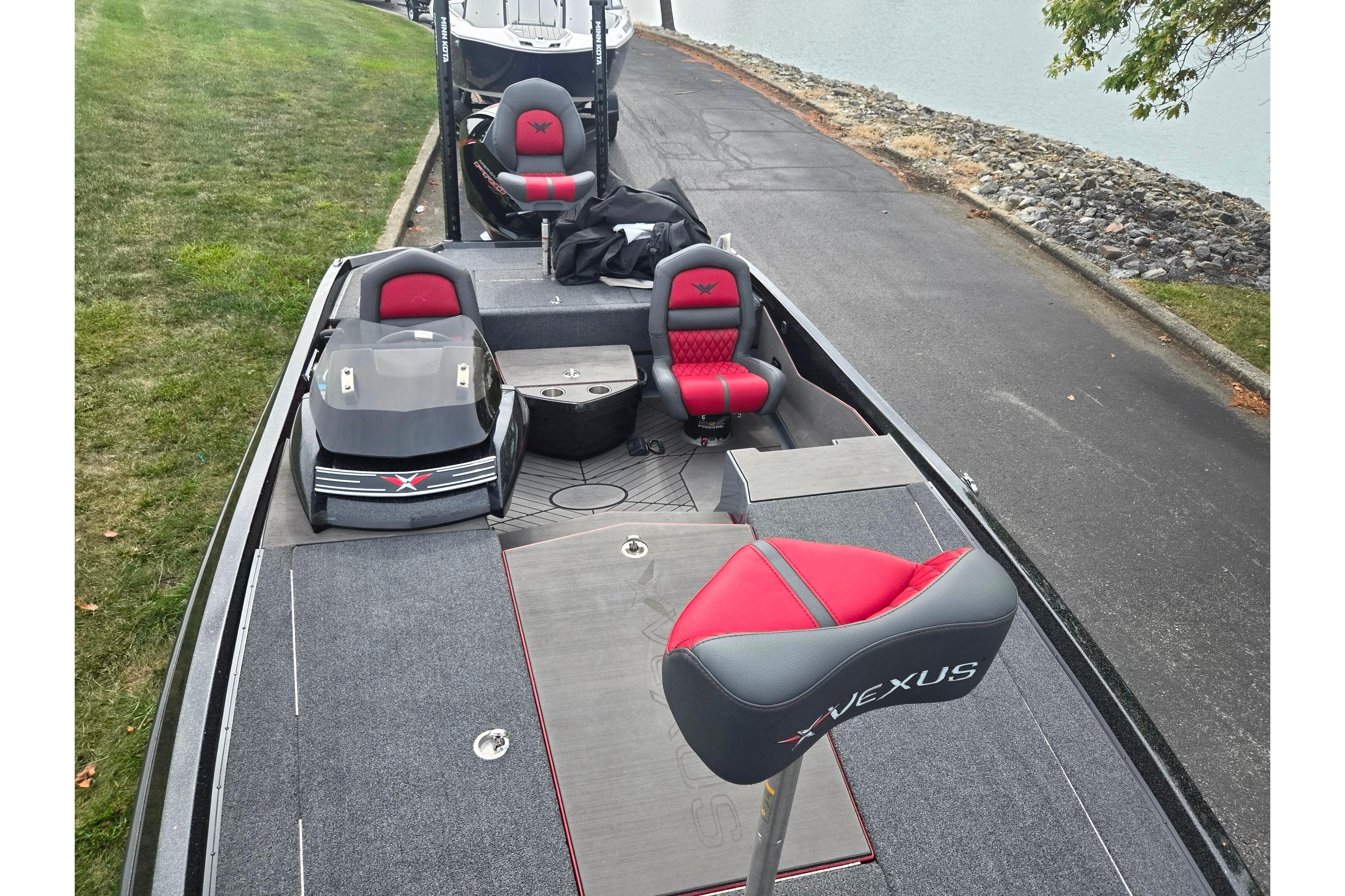 2022 Vexus VX20 boat with red and gray seating, parked near a lakeside.