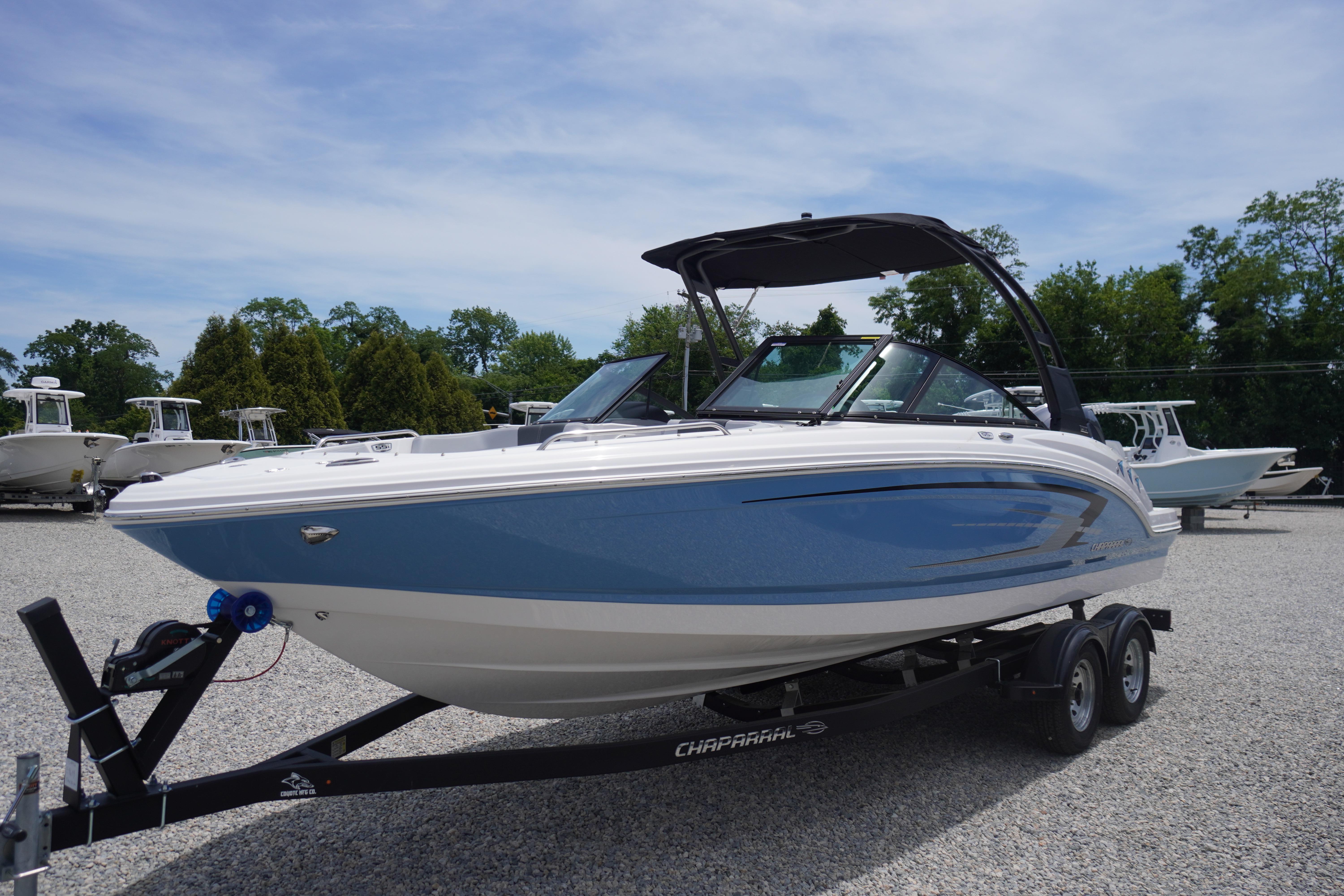2026 Chaparral 23 SSi OB boat on trailer, blue and white design, parked outdoors.