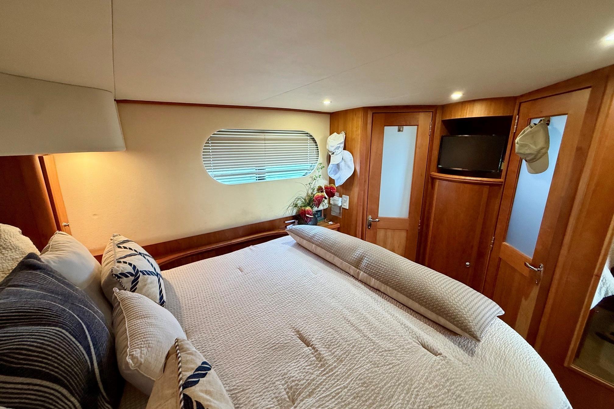 Luxurious bedroom interior of 2004 Silverton 39 Motor Yacht with cozy bedding and wooden accents.