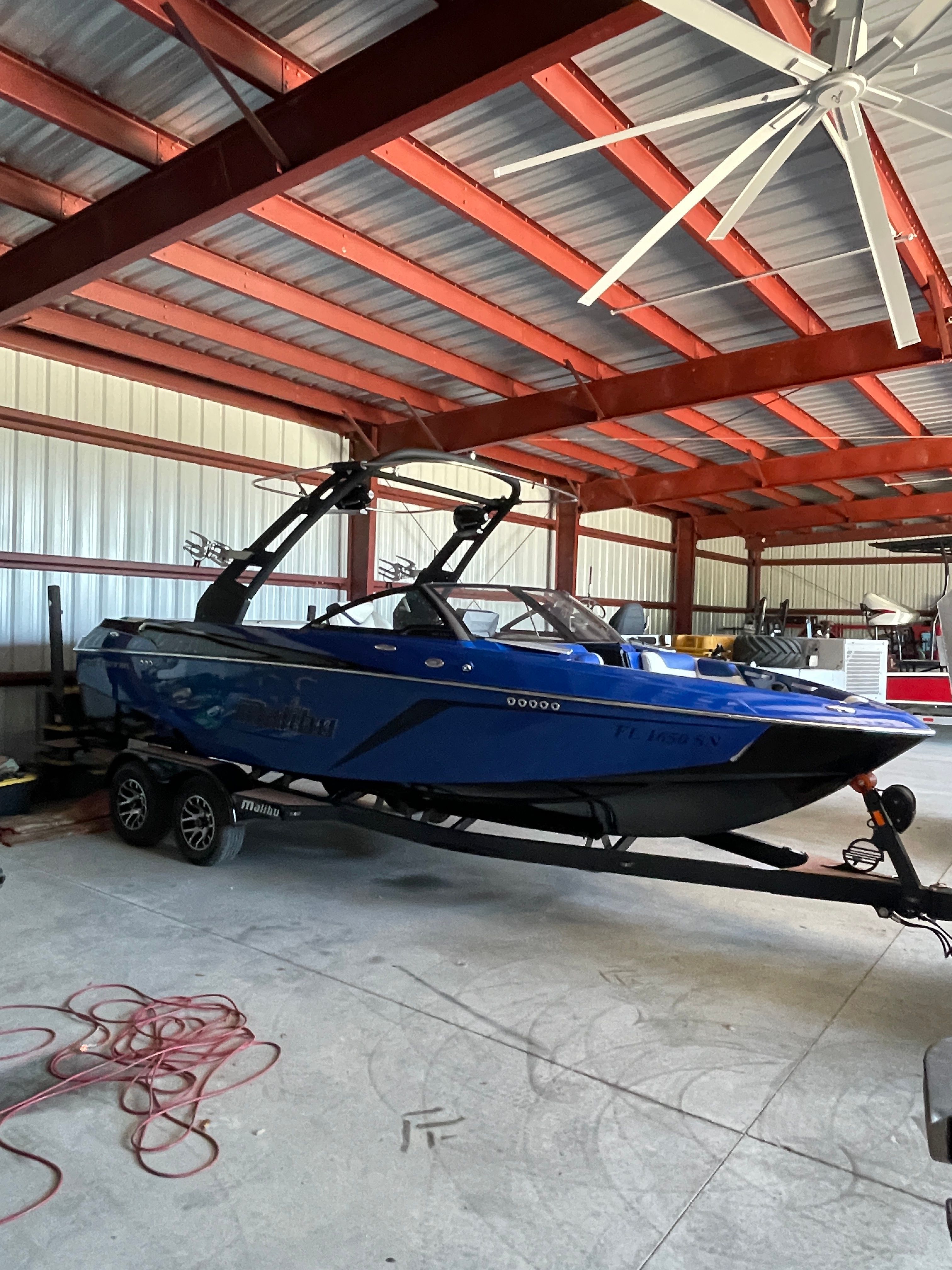 A blue 2019 Malibu Wakesetter 22 LSV sits on a trailer in a warehouse.