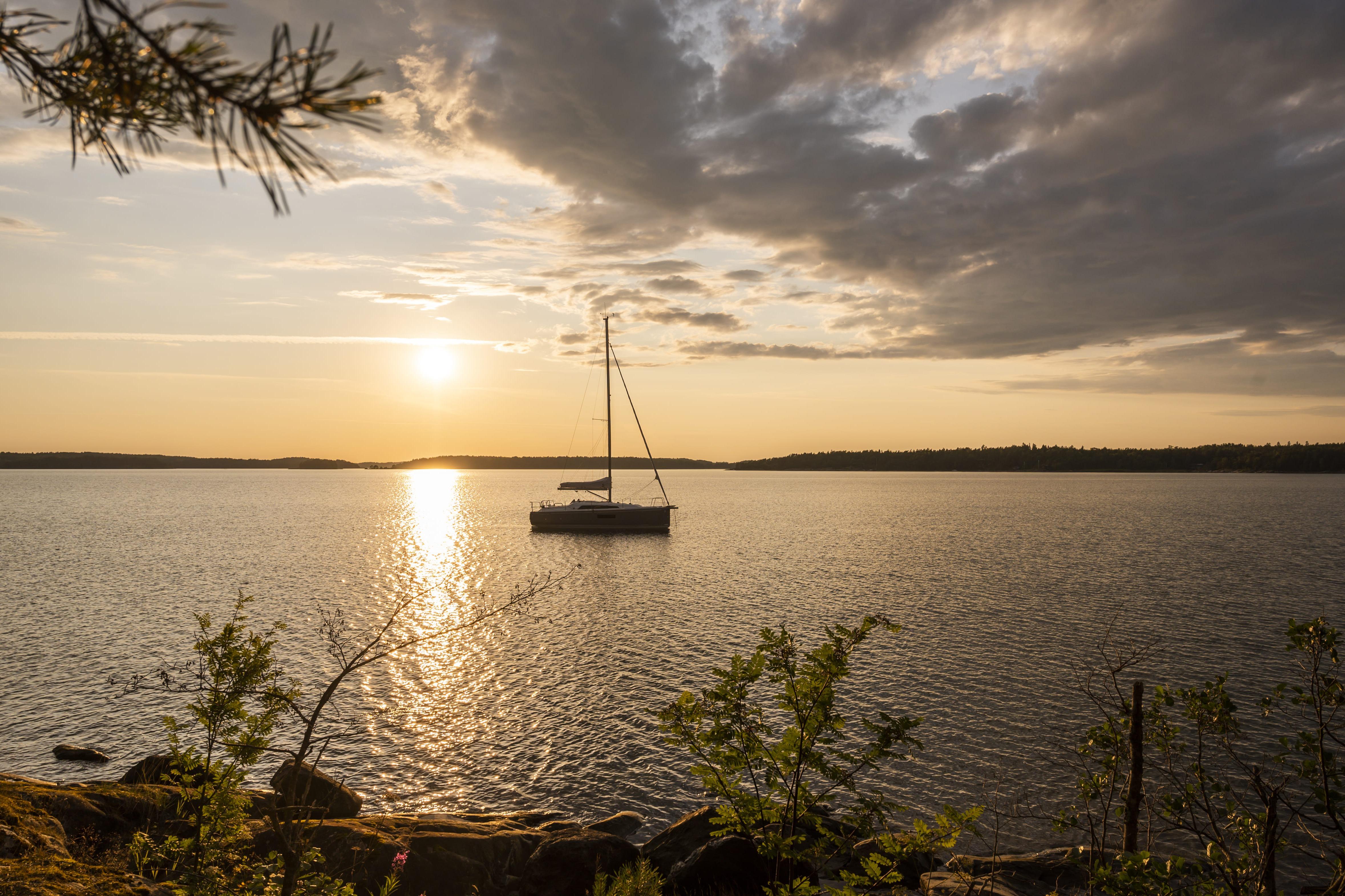 Sailboat Beneteau Oceanis 30.1, 2026 model, anchored at sunset on a tranquil lake.