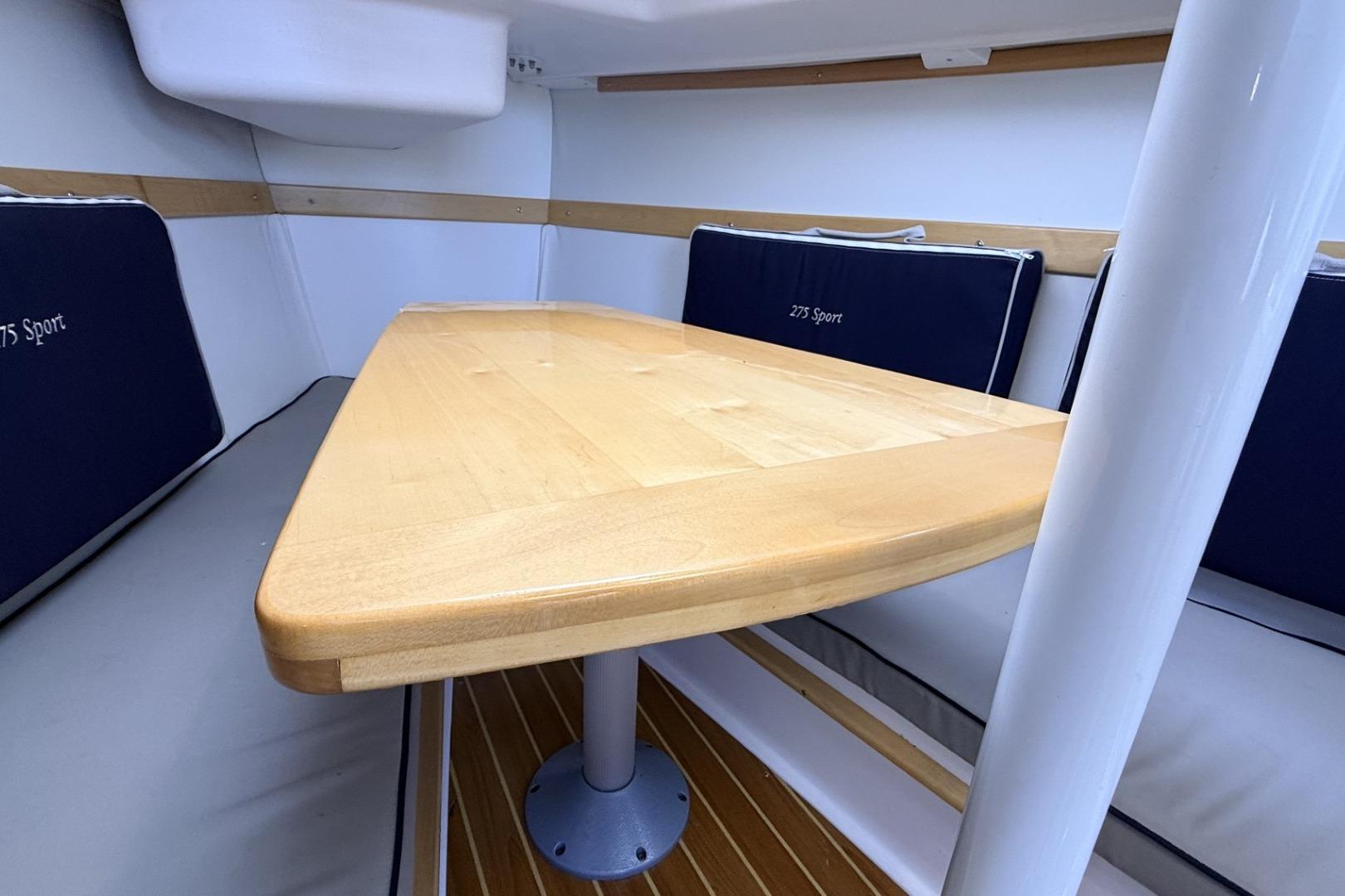 Interior of 2016 Catalina 275 Sport with wooden table and blue cushions.