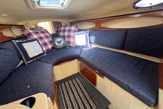 2003 Sea Ray 260 Sundancer cabin with blue seating, plaid pillows, and striped rug.