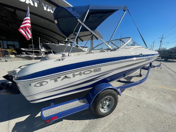 2012 Tahoe Q4 SS boat on trailer with blue accents and canopy, parked outdoors.