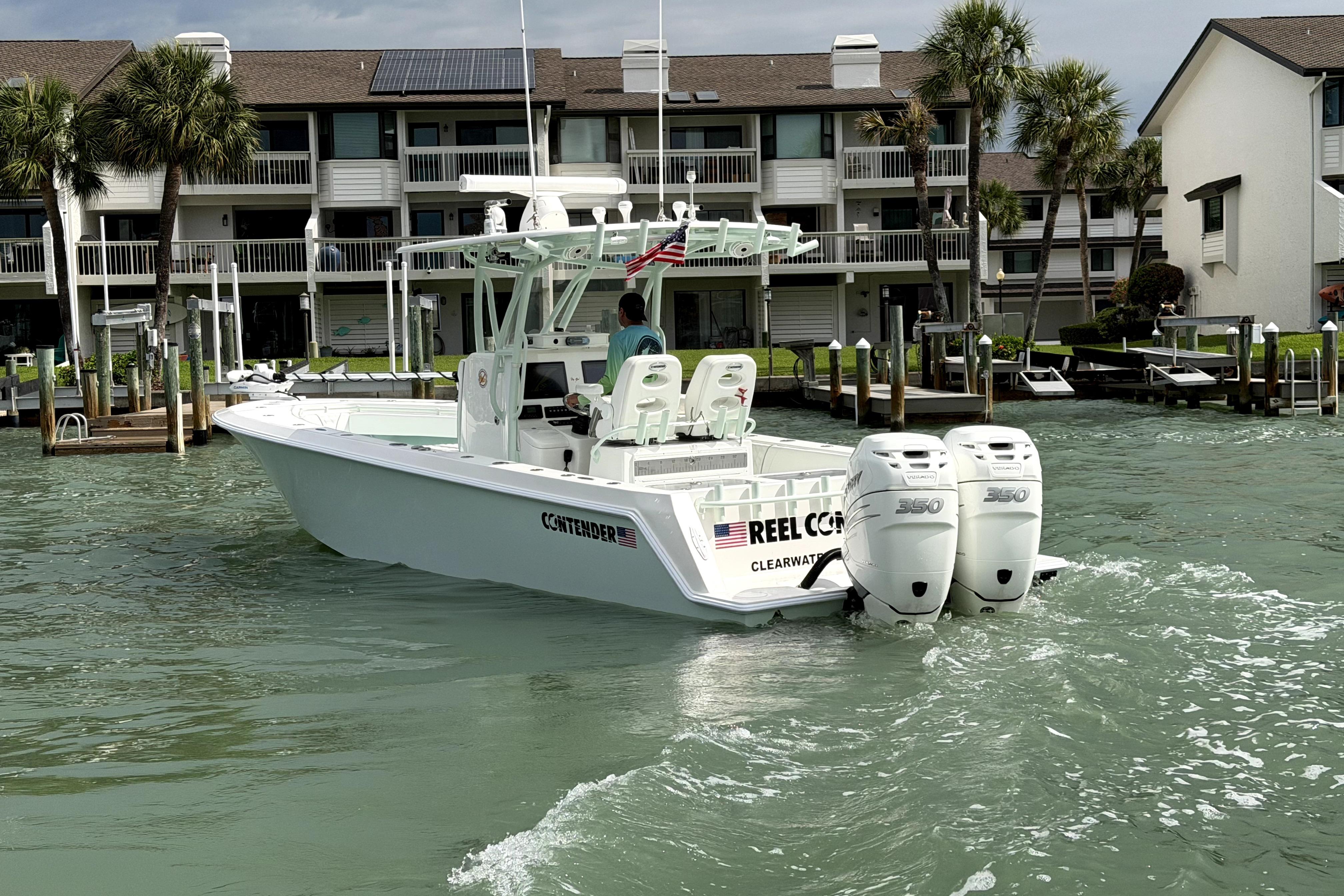 2019 Contender 30 ST boat with twin engines cruising near waterfront homes.