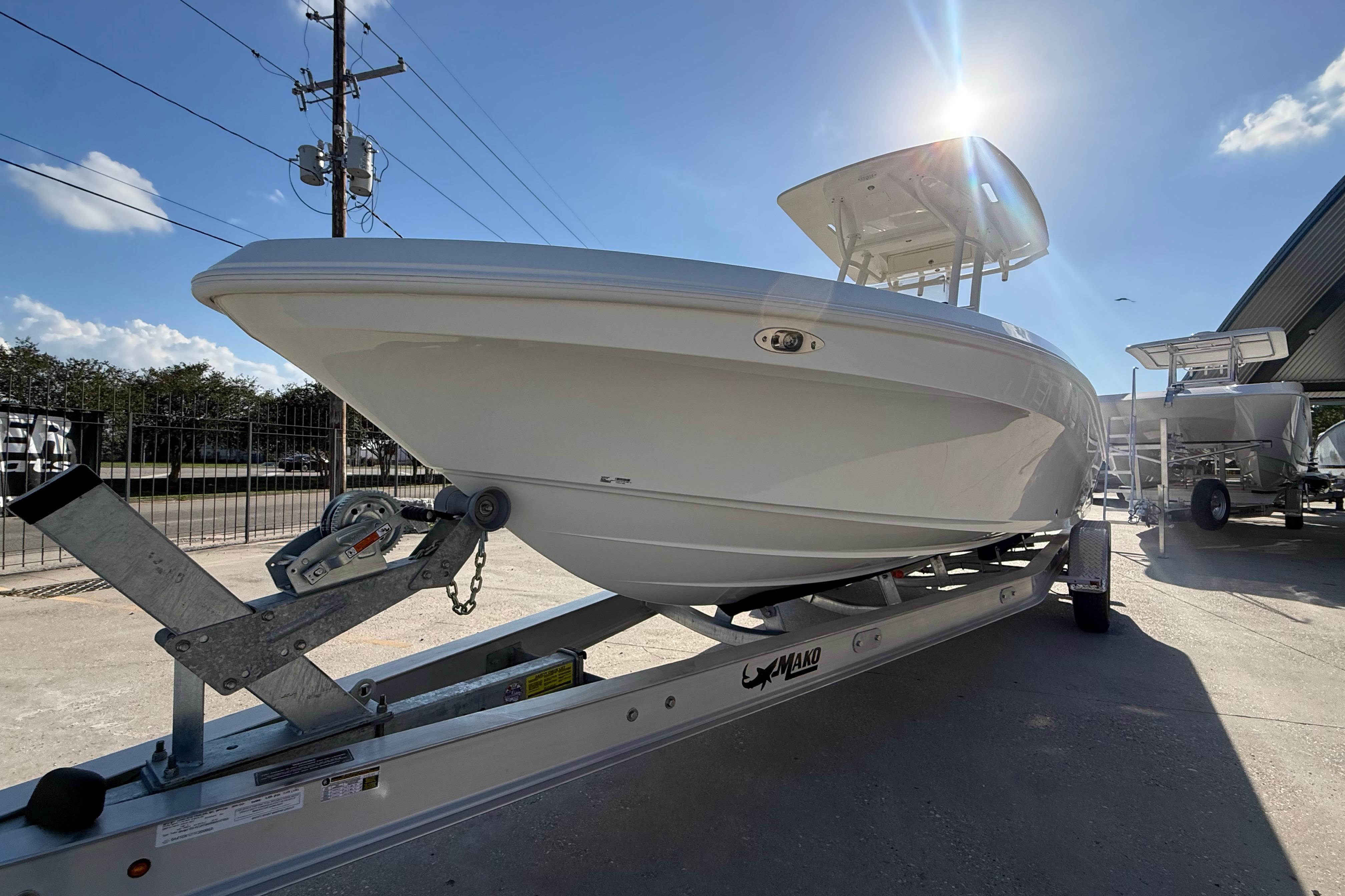 2026 Mako 24 APEX boat on trailer under sunny sky, showcasing sleek design.