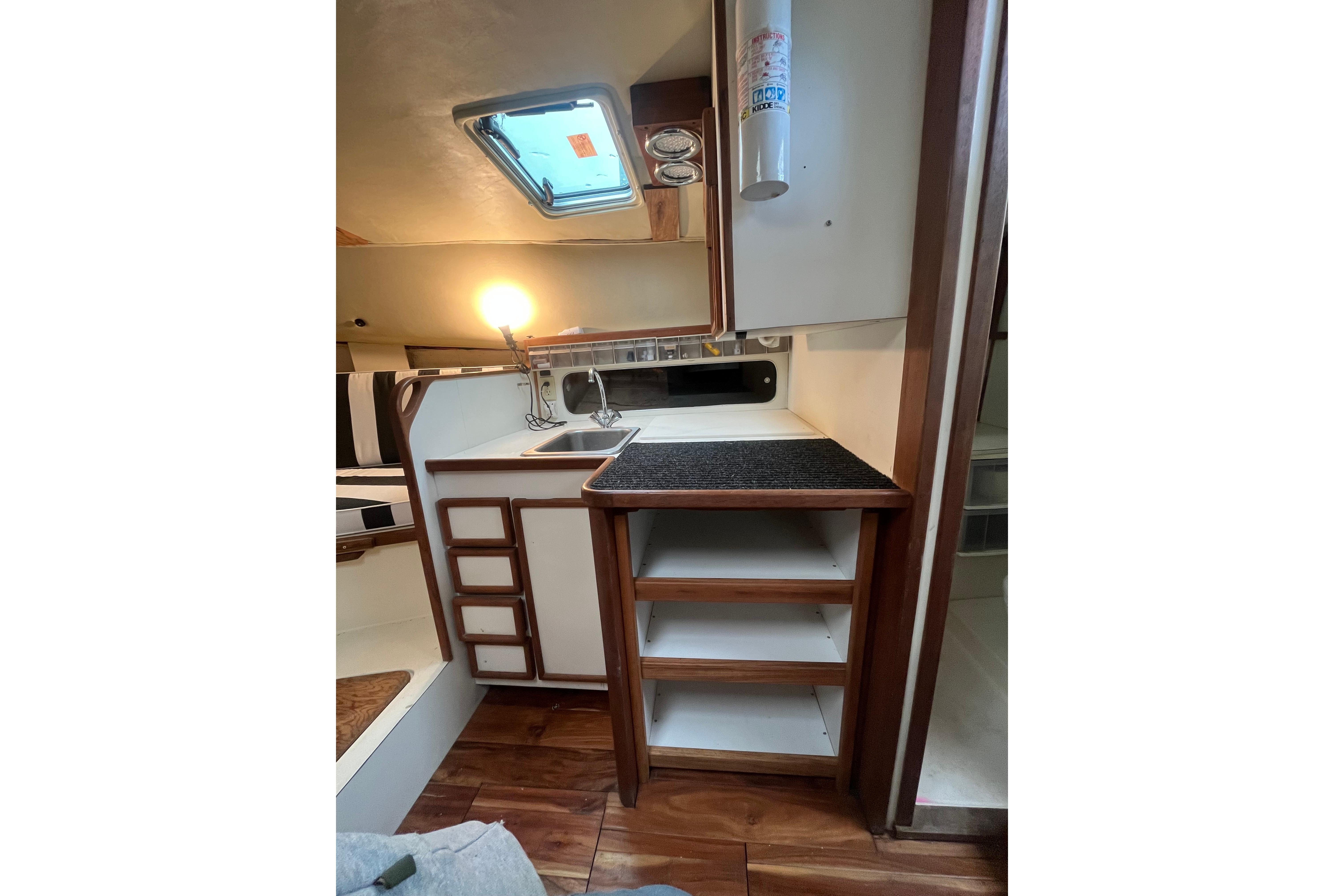1989 Blackfin 31 Combi boat interior with kitchenette, sink, and wooden cabinetry.
