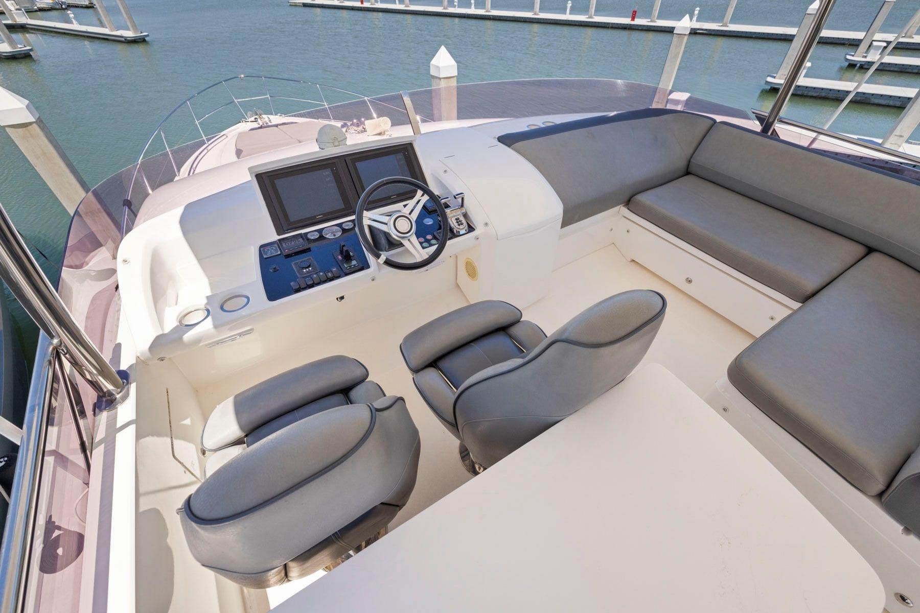 Flybridge of 2015 Princess 60 Motor Yacht with helm, seating, and marina view.